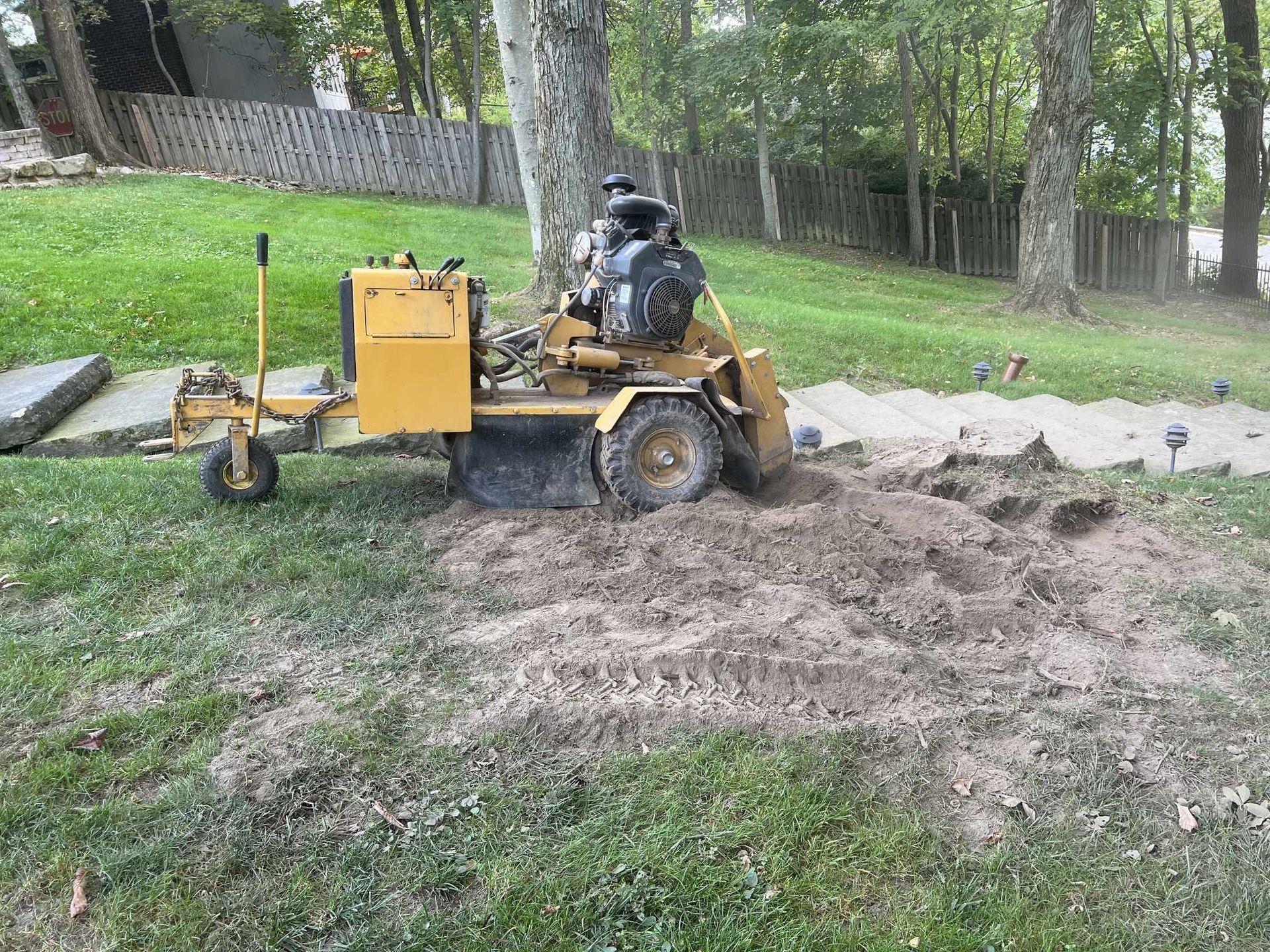 A stump grinder is sitting in the middle of a lush green field.
