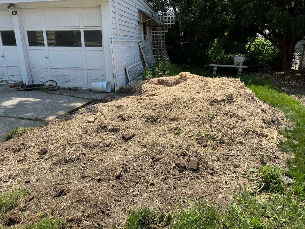 A pile of dirt is sitting in front of a garage.