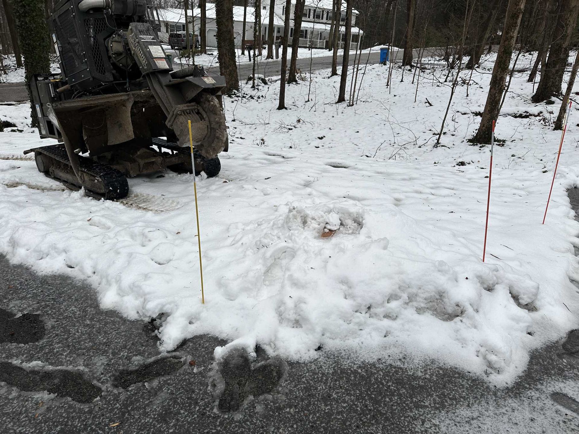 A snow blower is sitting on the side of the road in the snow.
