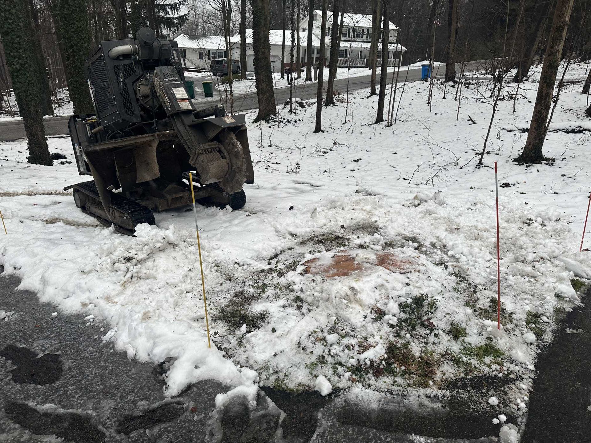 A tractor is sitting in the snow next to a tree stump.