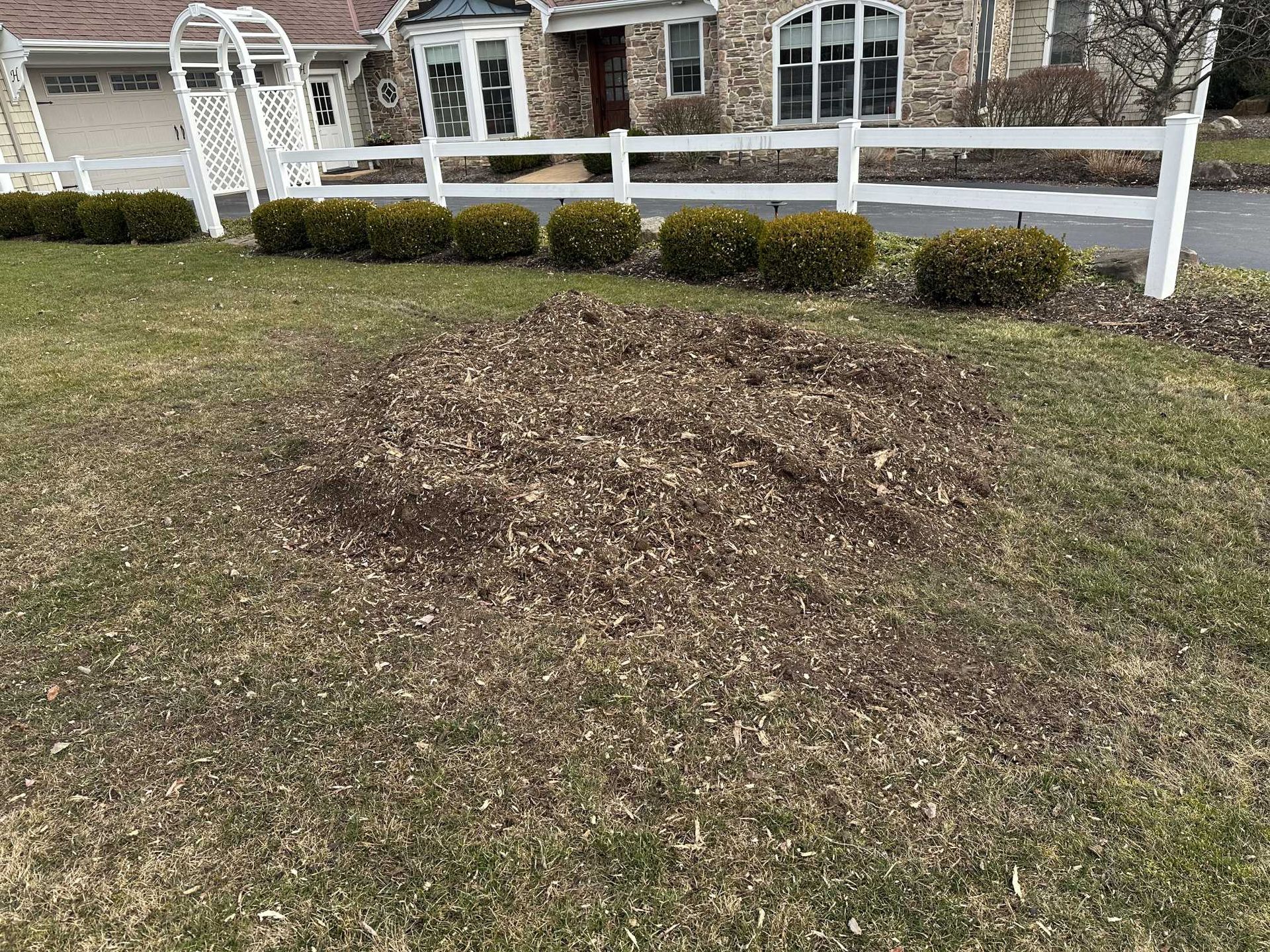 A white fence surrounds a lush green lawn in front of a house.