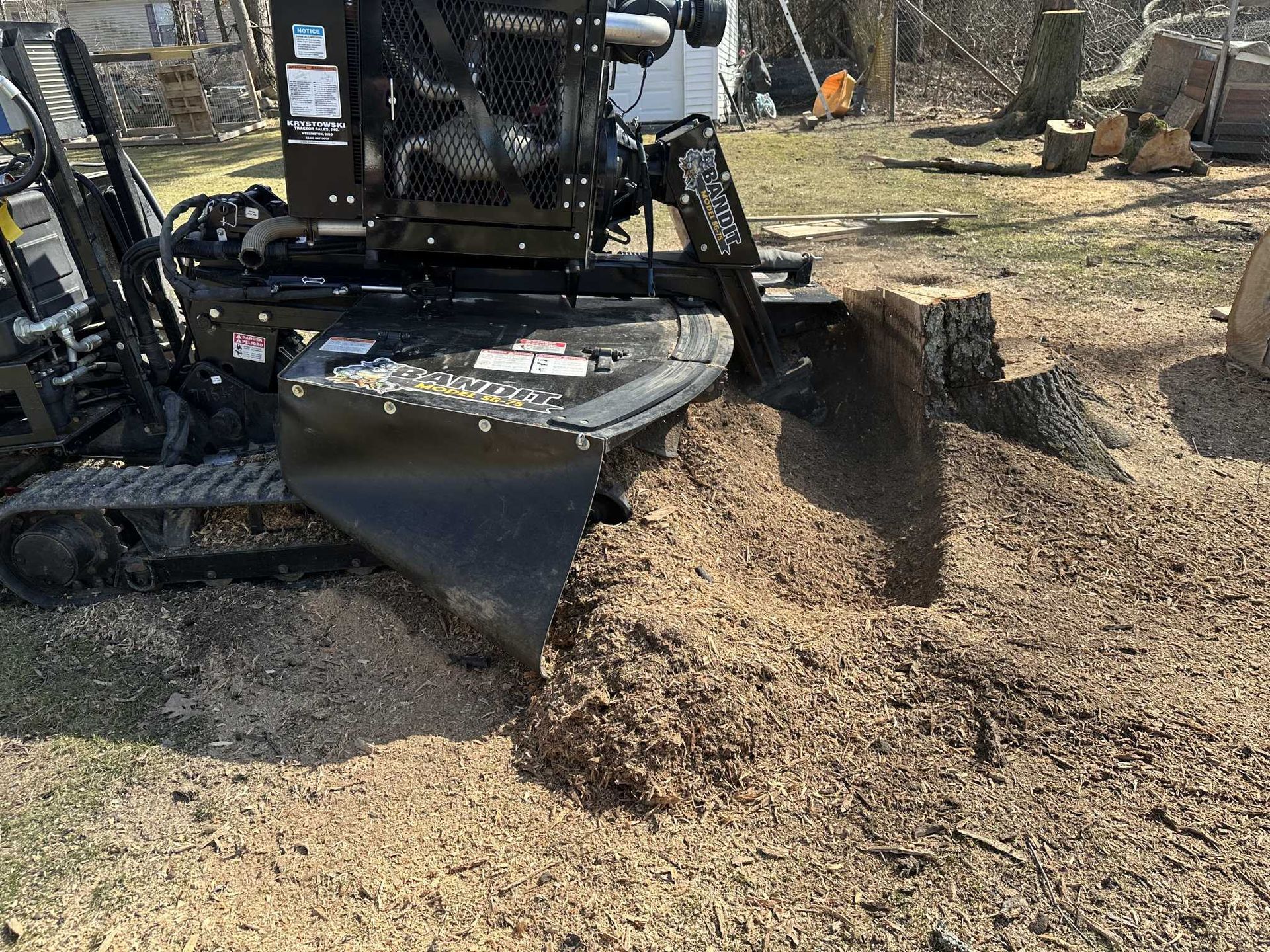 A machine is stump grinding a tree stump in a yard.