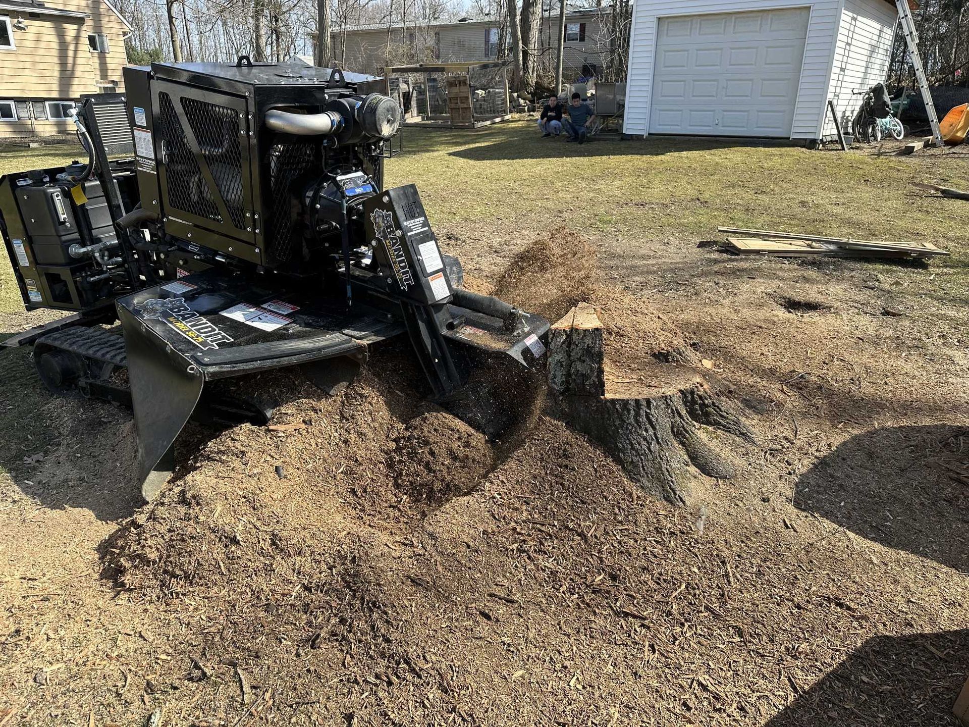 A machine is stump grinding a tree stump in a yard.