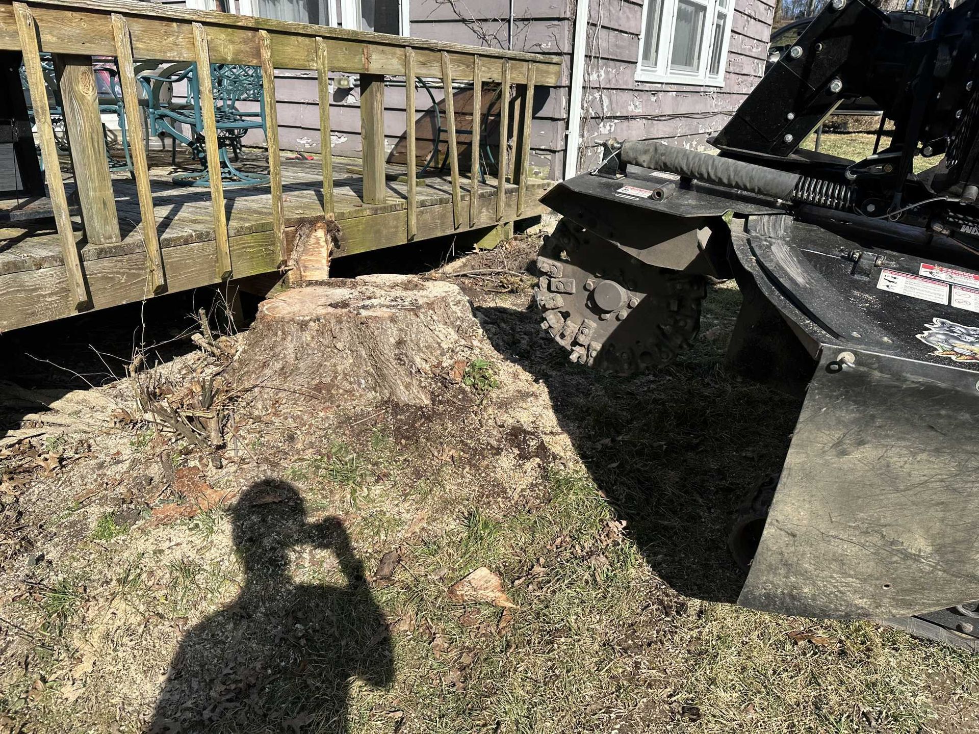 A person is taking a picture of a pile of wood next to a house.