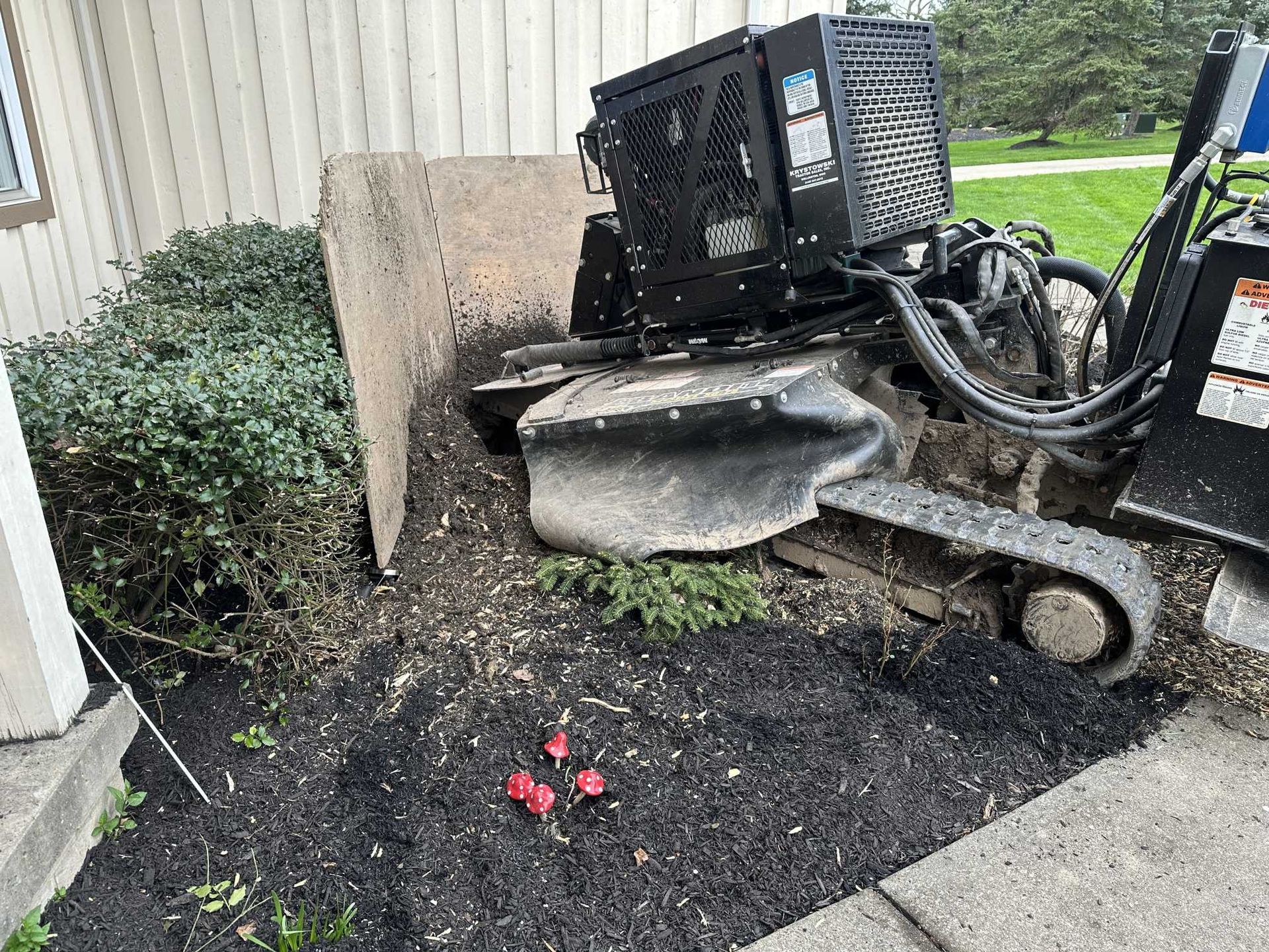 A stump grinder is sitting on the sidewalk next to a house.