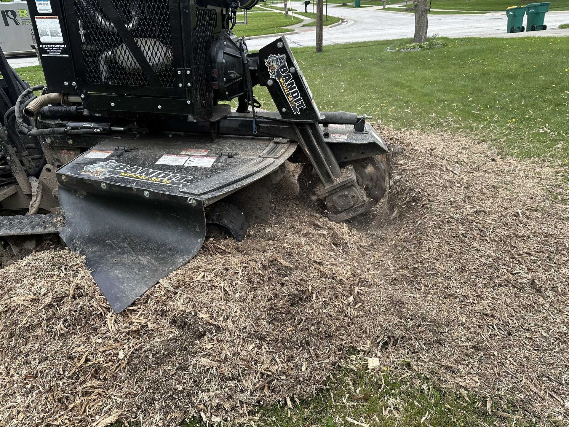 A stump grinder is cutting a tree stump in a park.