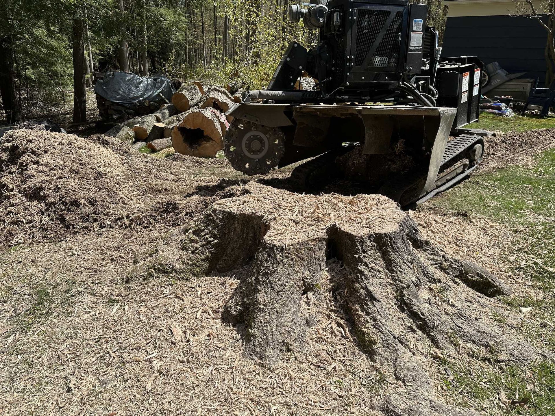A bulldozer is stump grinding a tree stump in a yard.