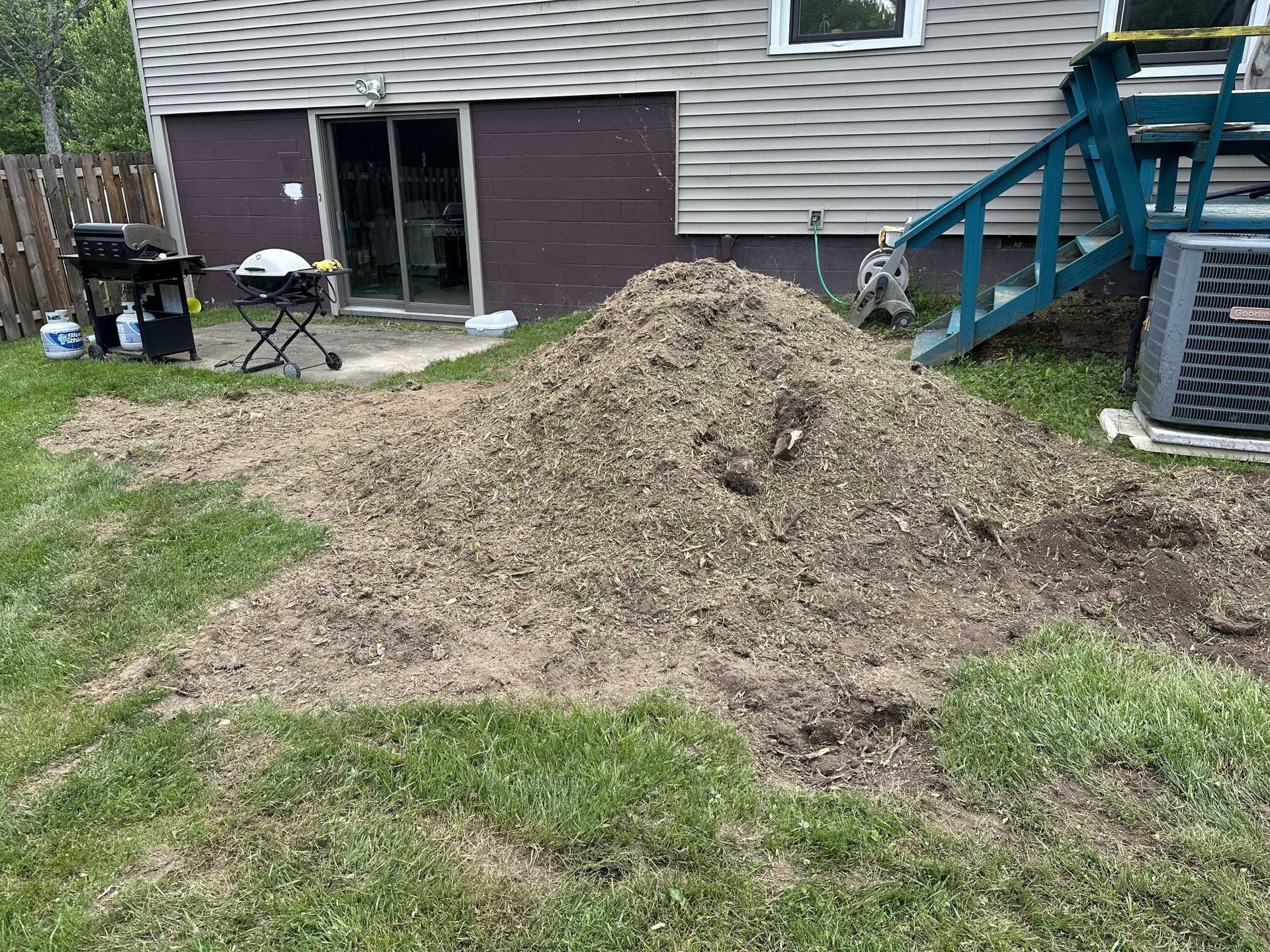 A pile of dirt is sitting in the grass in front of a house.