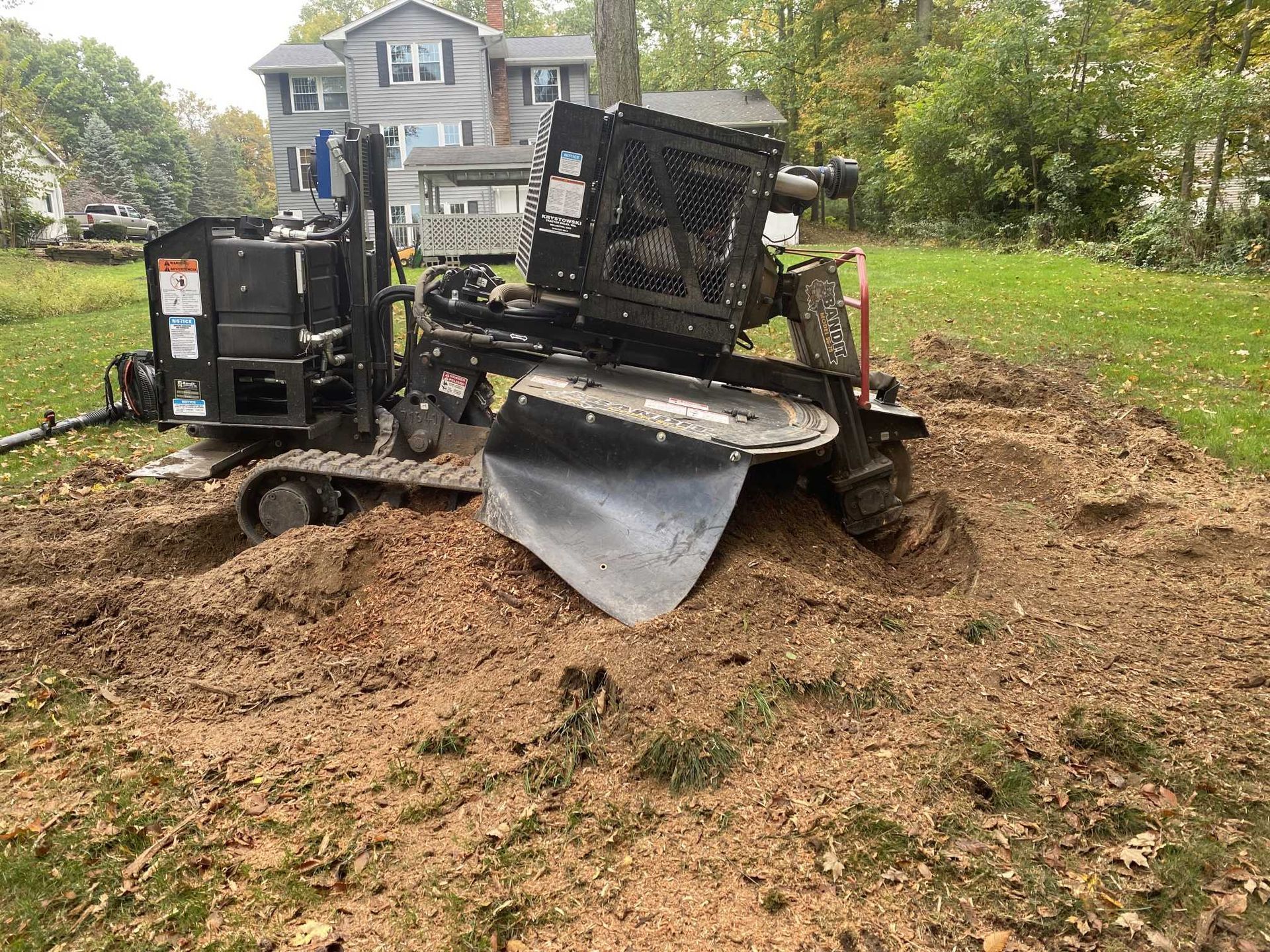 A stump grinder is working on a tree stump in a yard.