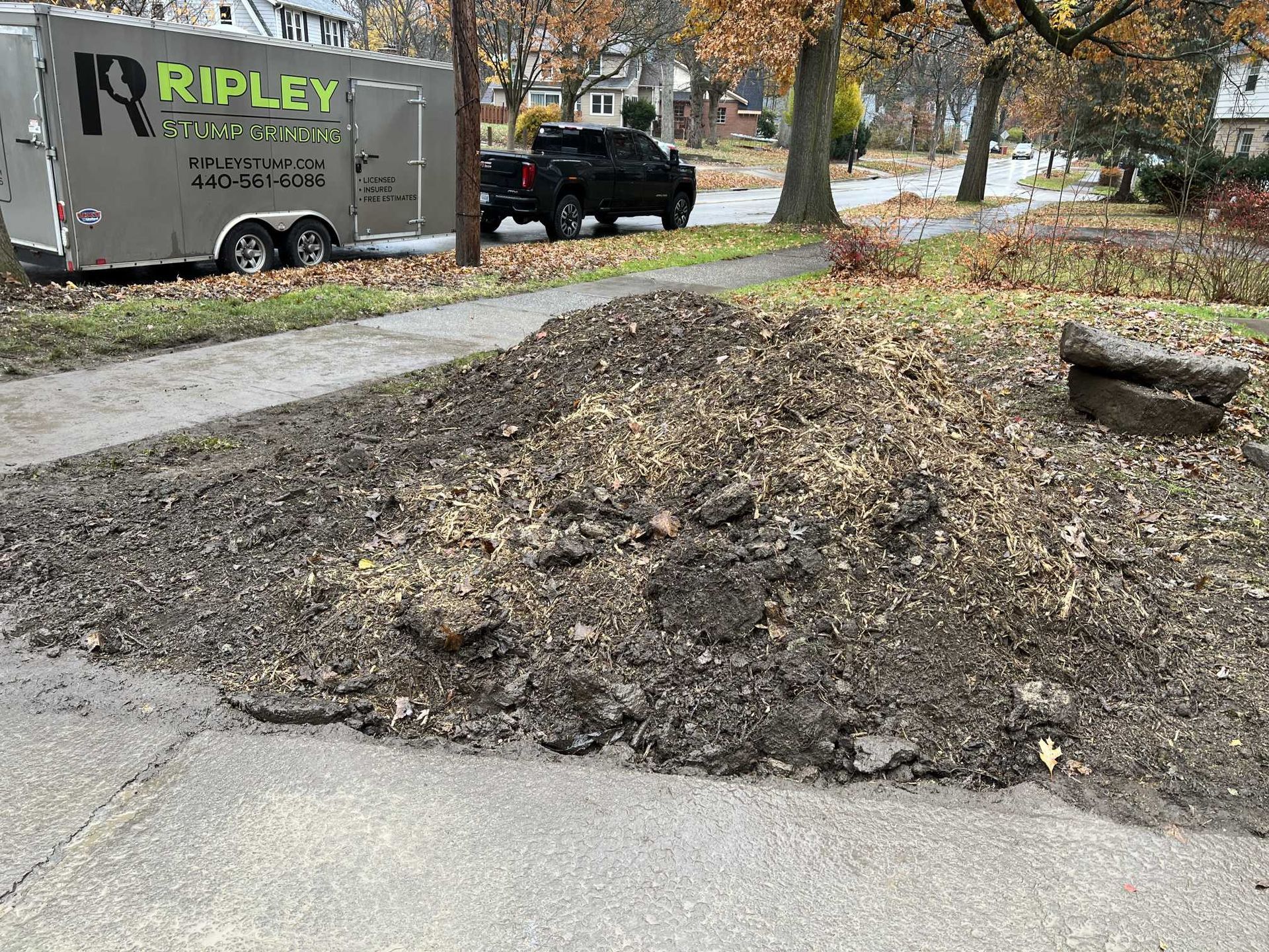 A large pile of dirt is sitting on the side of the road next to a trailer.
