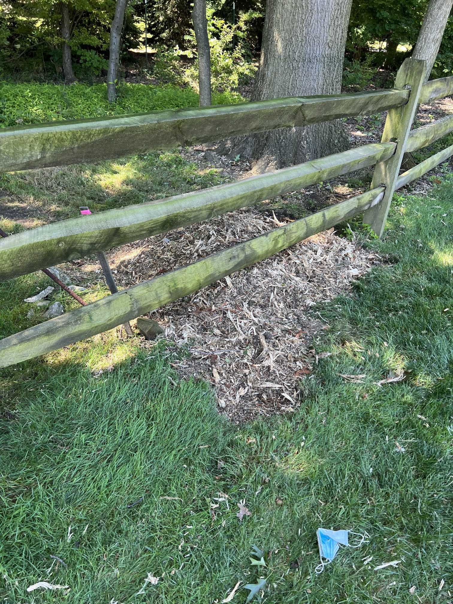 A wooden fence is sitting in the middle of a lush green field.