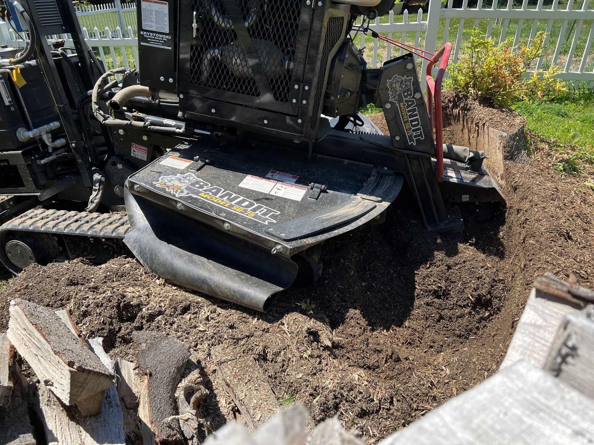 A tractor is digging a hole in the ground in a yard.