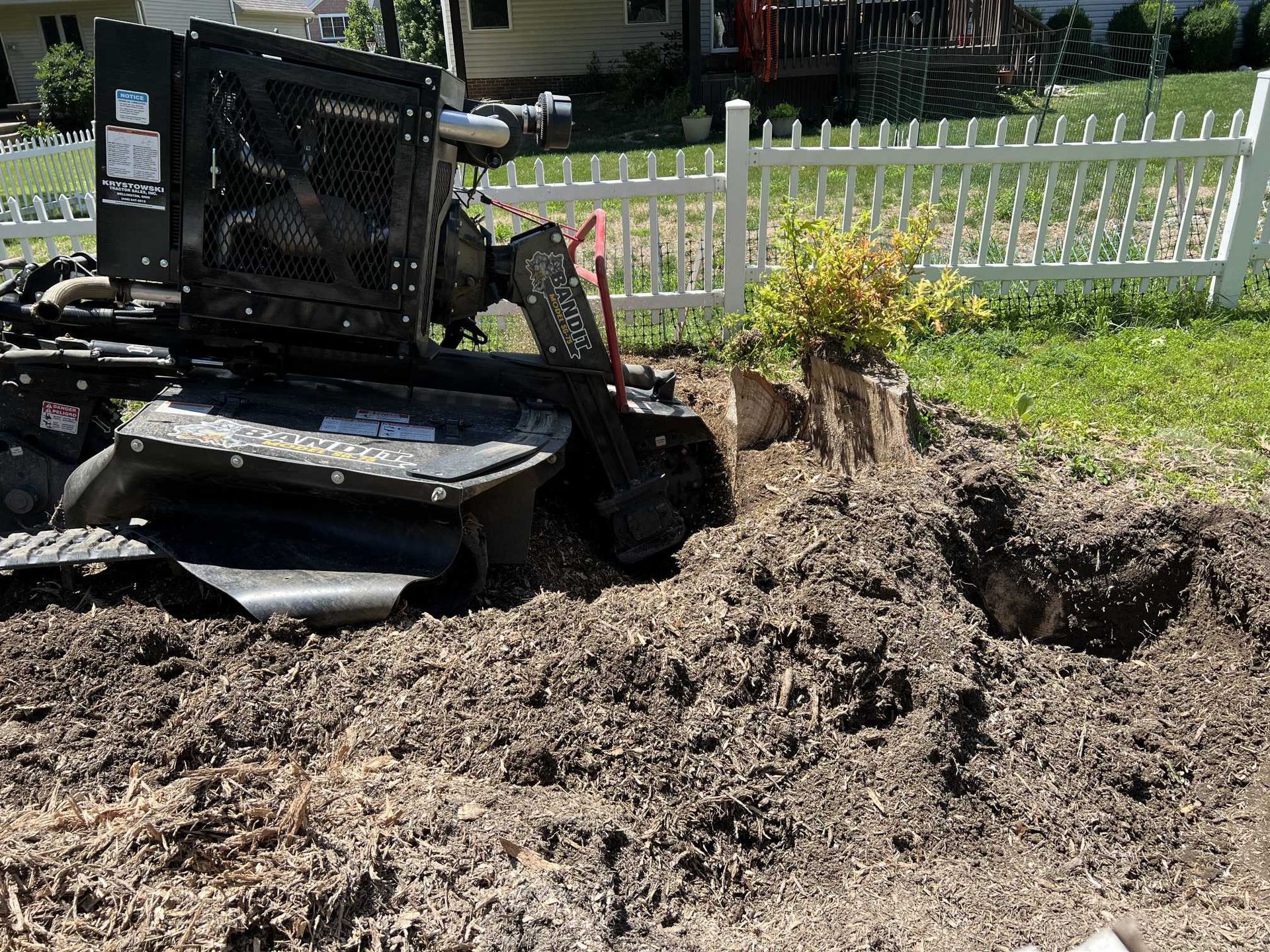 A stump grinder is being used to remove a tree stump in a yard.