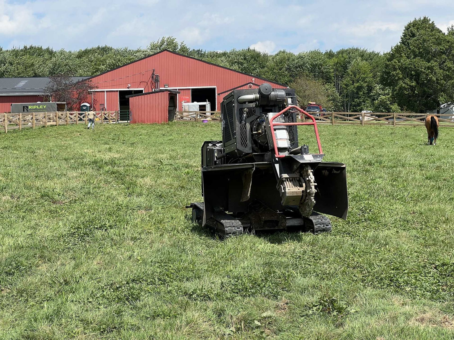 A tractor is driving through a grassy field in front of a barn.