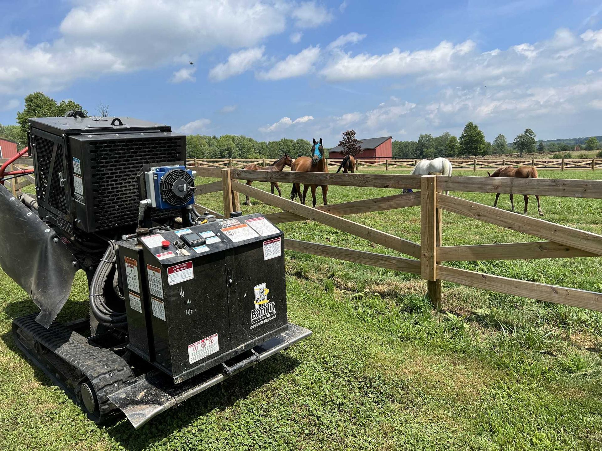 A bulldozer is parked in a grassy field with horses in the background.