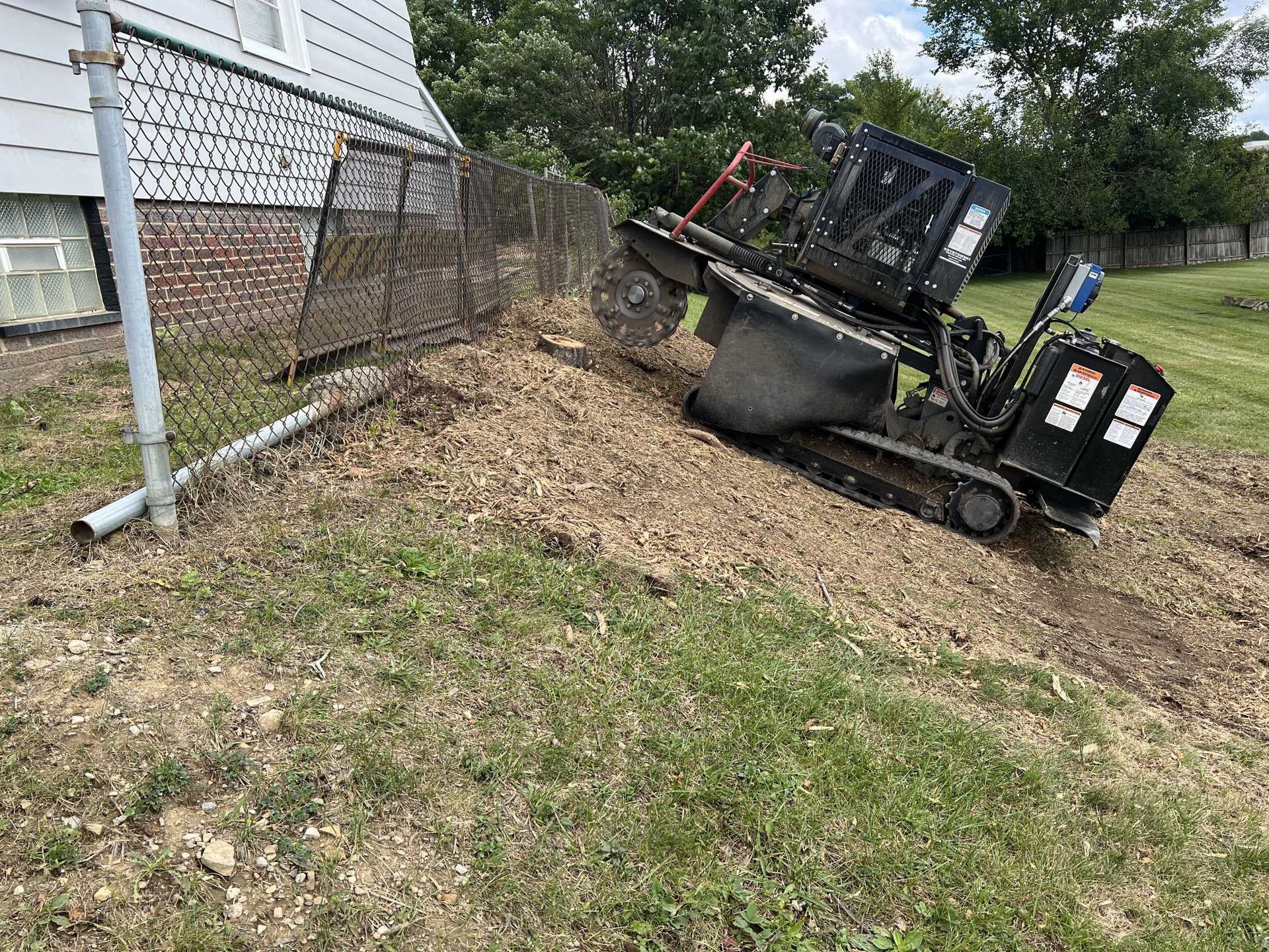 A bulldozer is sitting on top of a hill next to a house.