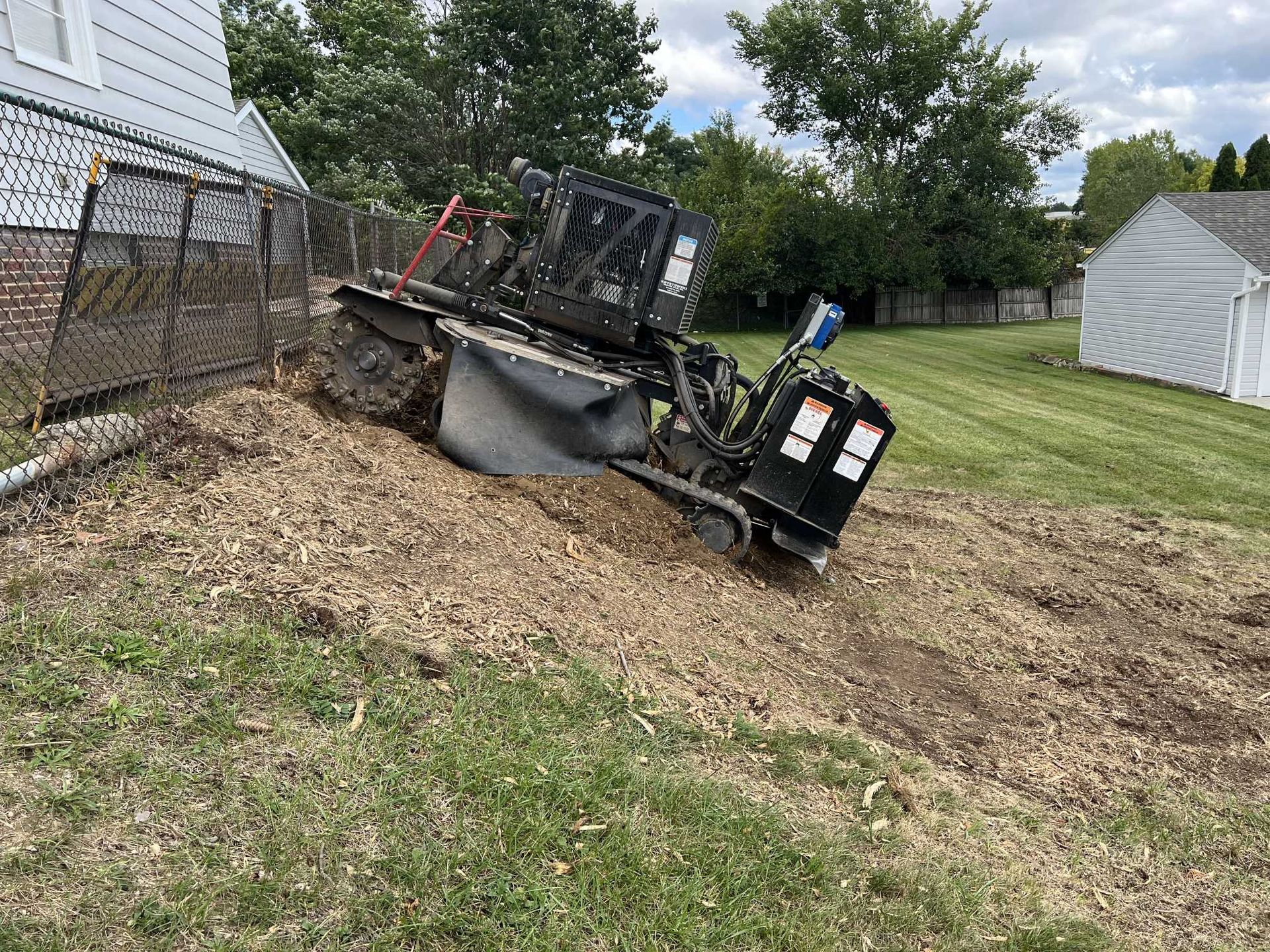 A stump grinder is sitting on top of a tree stump in a yard.