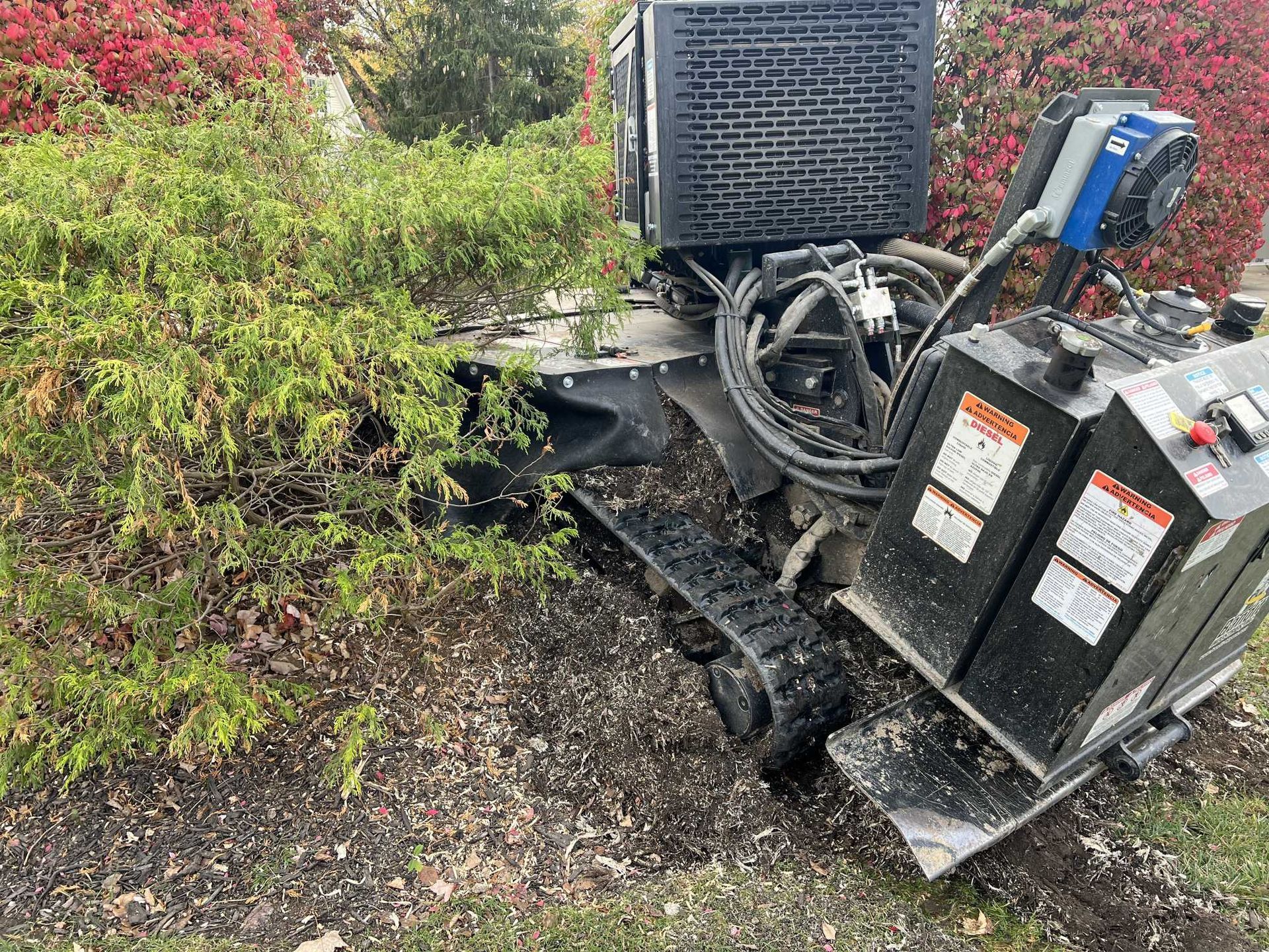 A machine is sitting on the ground next to a bush.