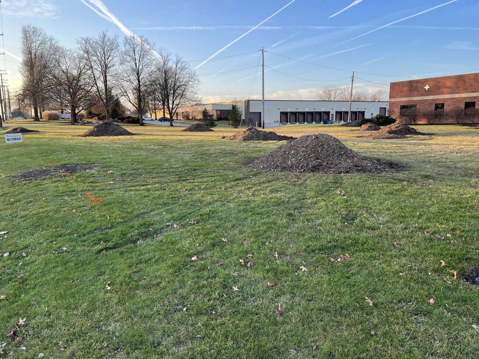 A large pile of dirt is sitting in the middle of a lush green field.