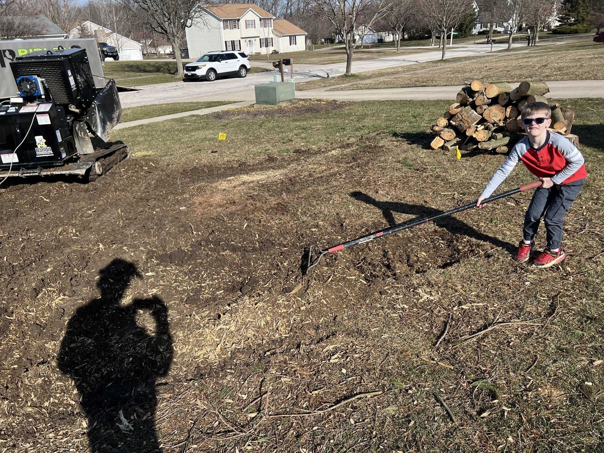 A young boy is playing with a rake in a field.