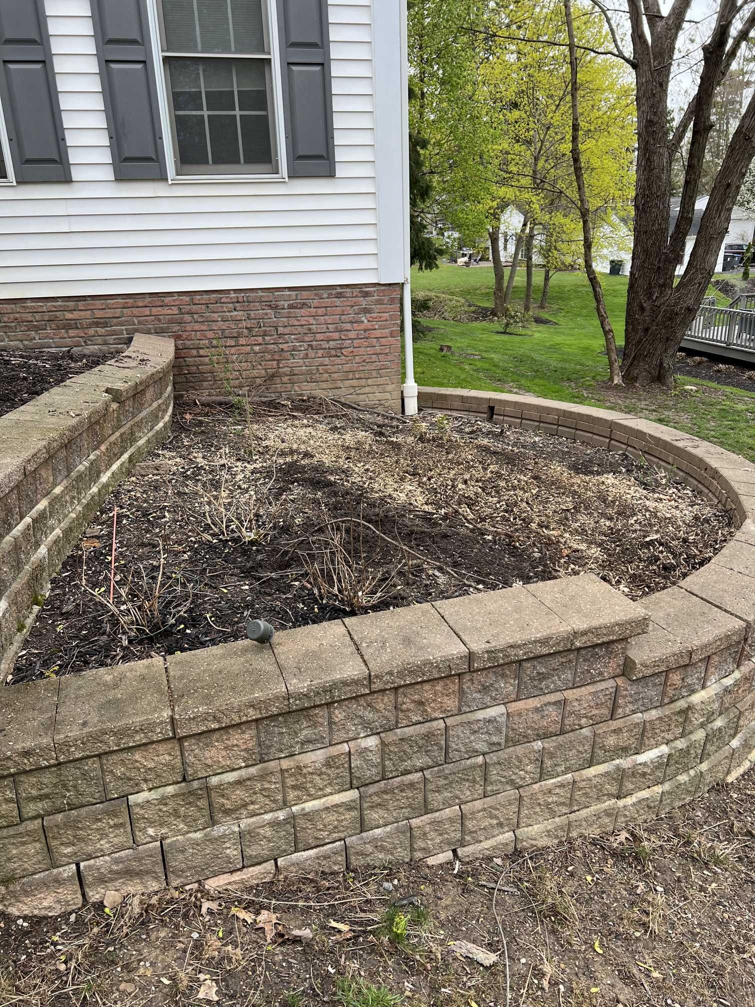 A brick wall surrounding a garden in front of a house.
