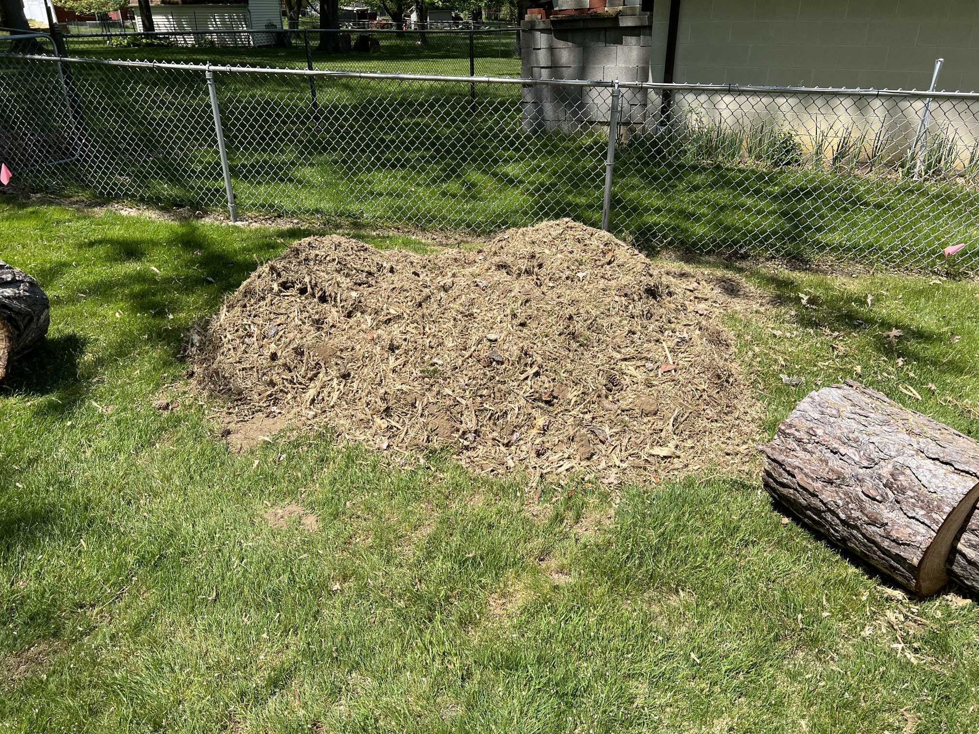 A pile of wood chips is sitting on top of a lush green lawn.