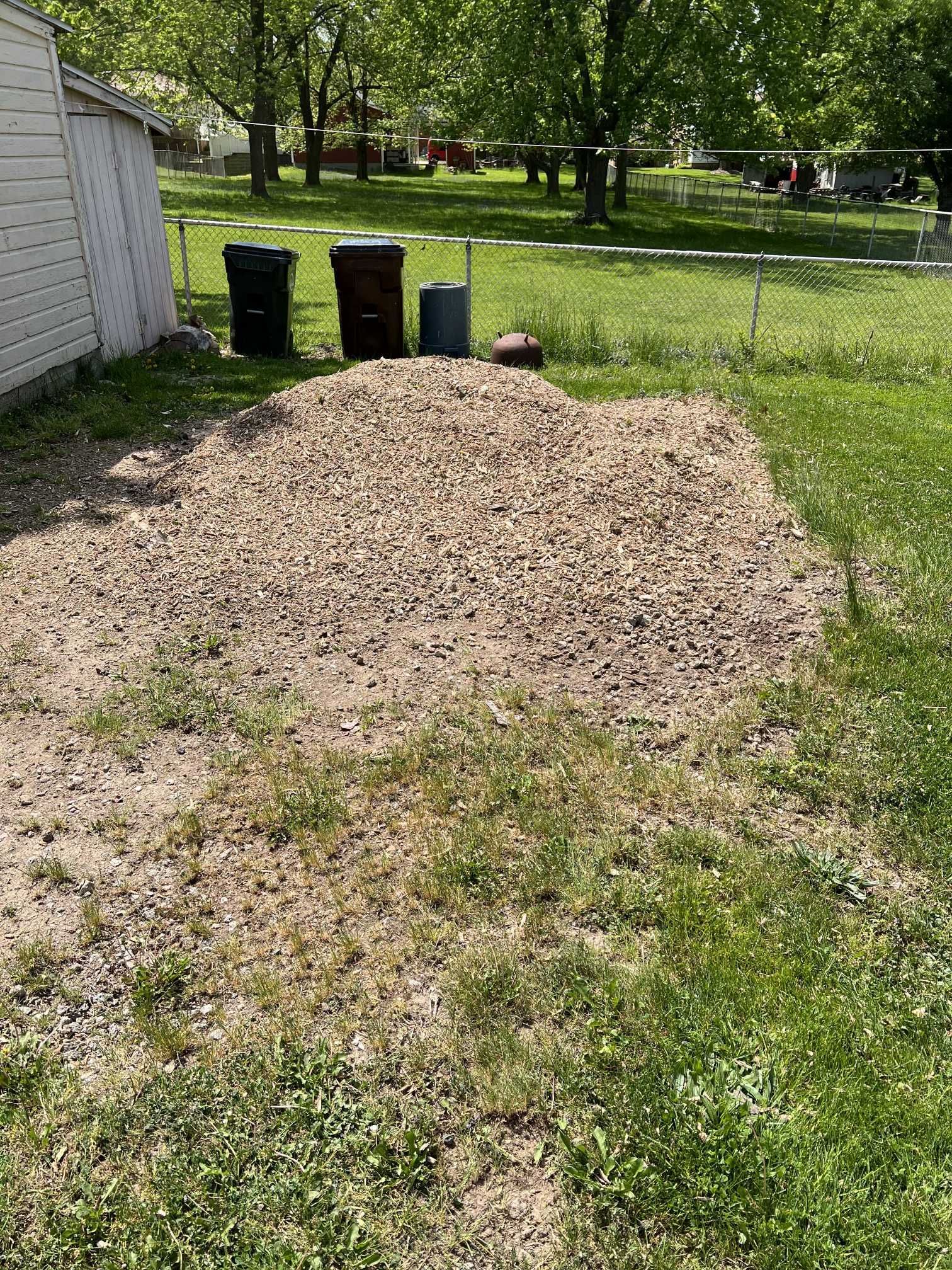 A pile of gravel is sitting in the middle of a lush green yard.