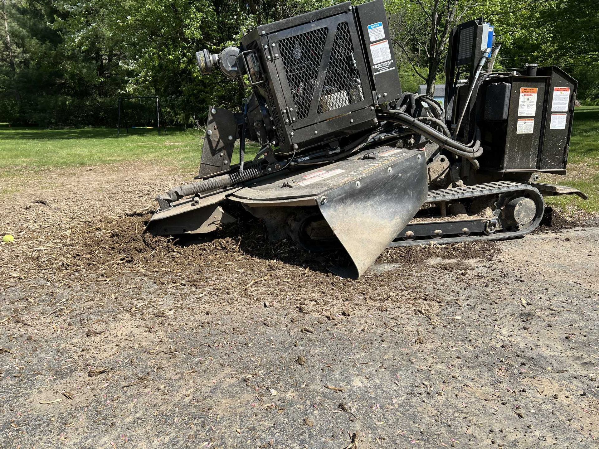 A stump grinder is sitting on the ground in a park.