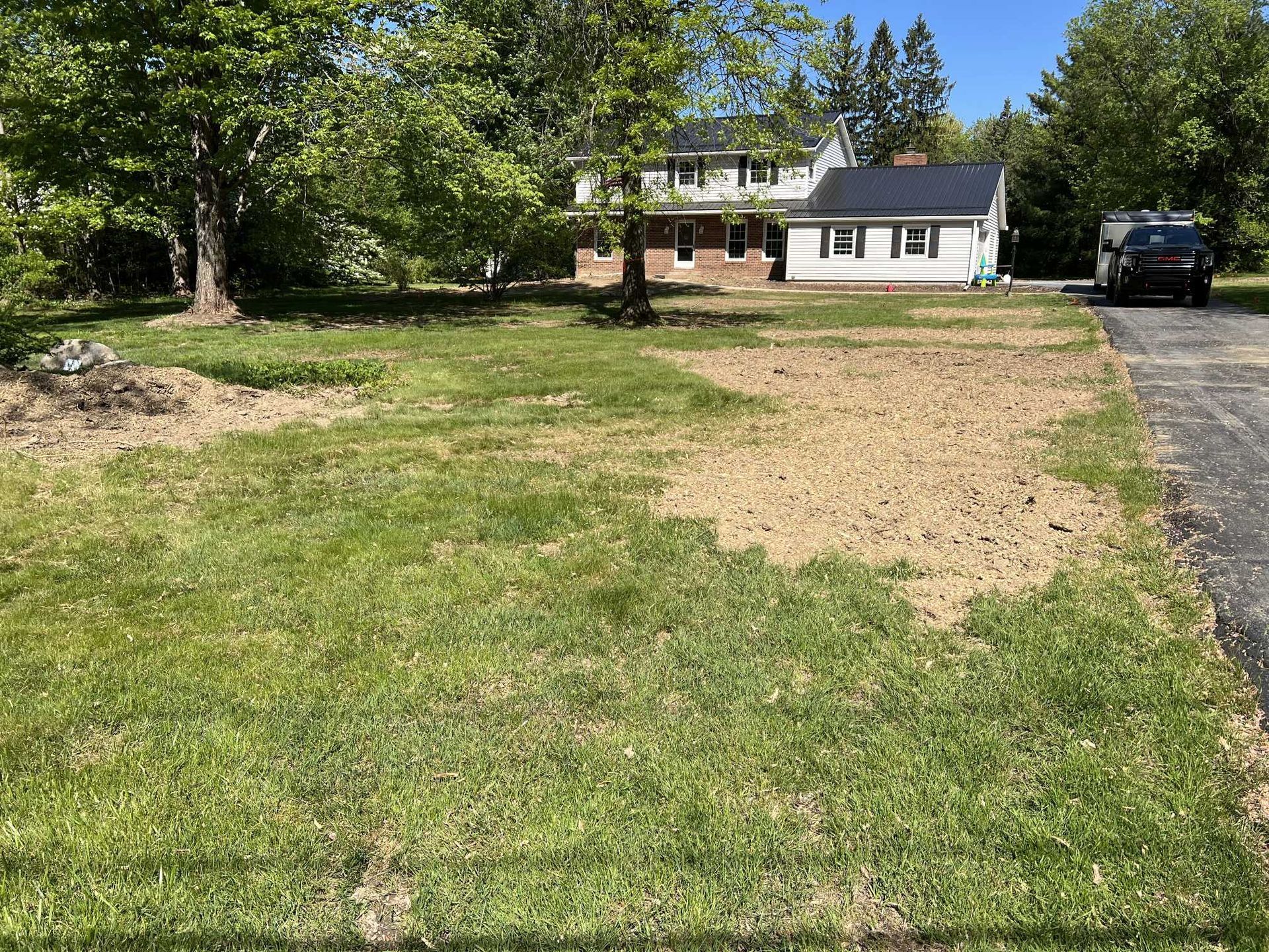 A large lawn with a house in the background and a car parked in front of it.