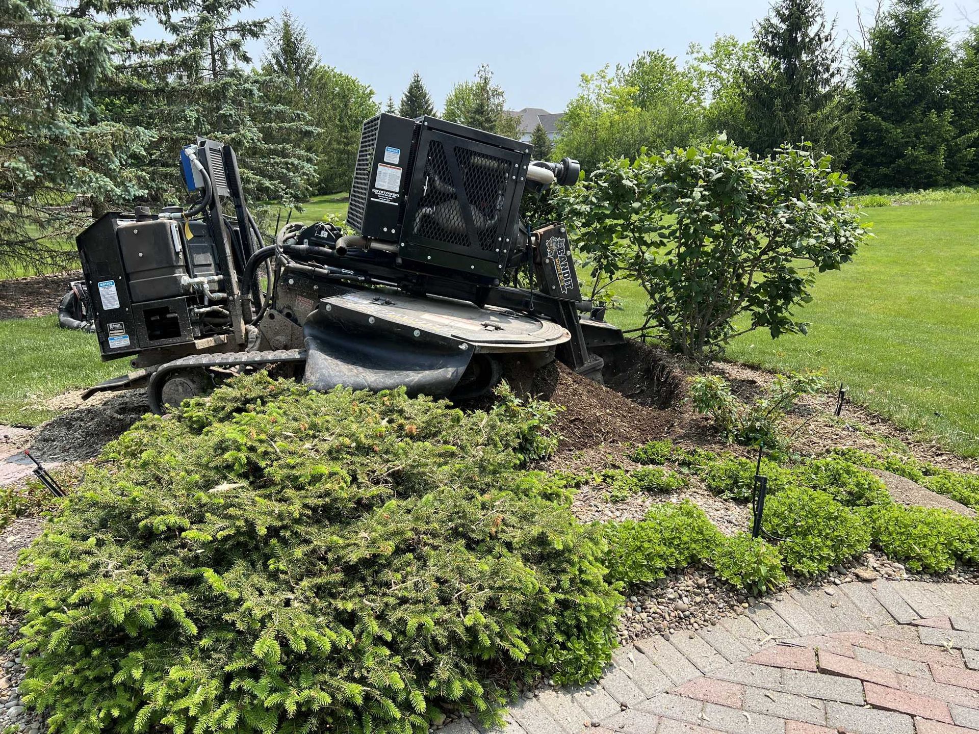 A tree stump grinder is sitting in the middle of a lush green field.