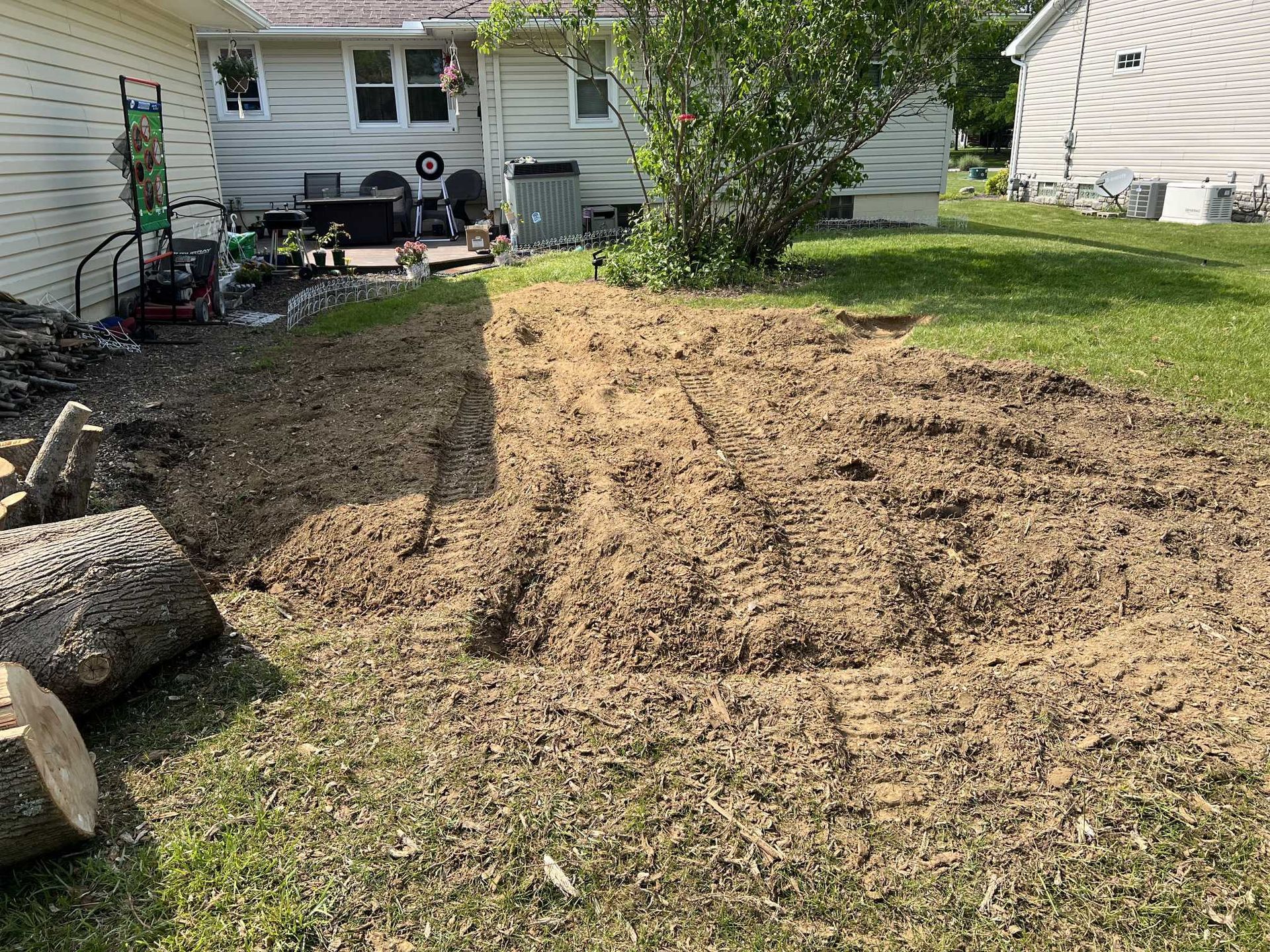 A large pile of dirt is in the backyard of a house.