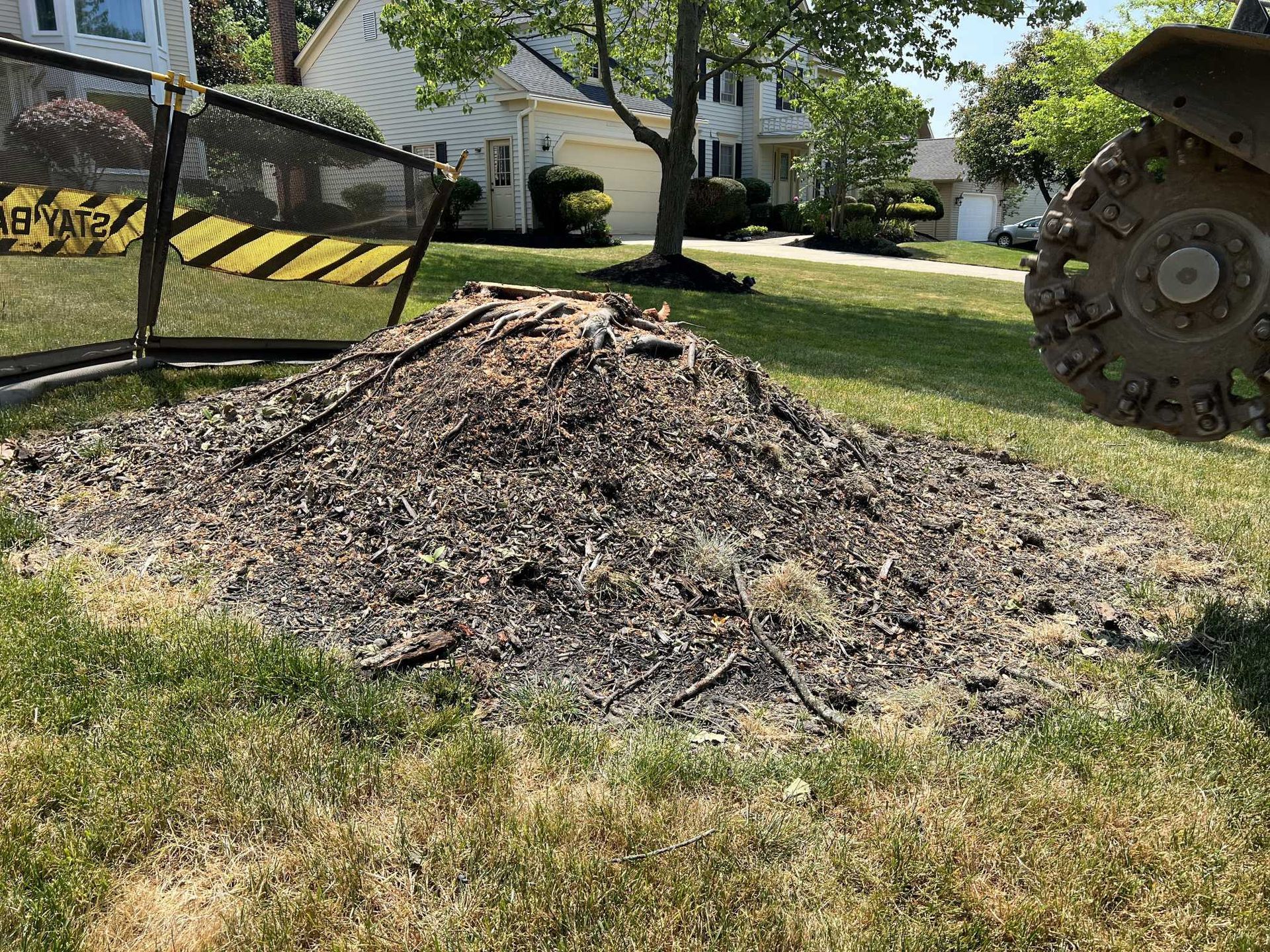 A pile of wood is sitting in the grass in front of a house.