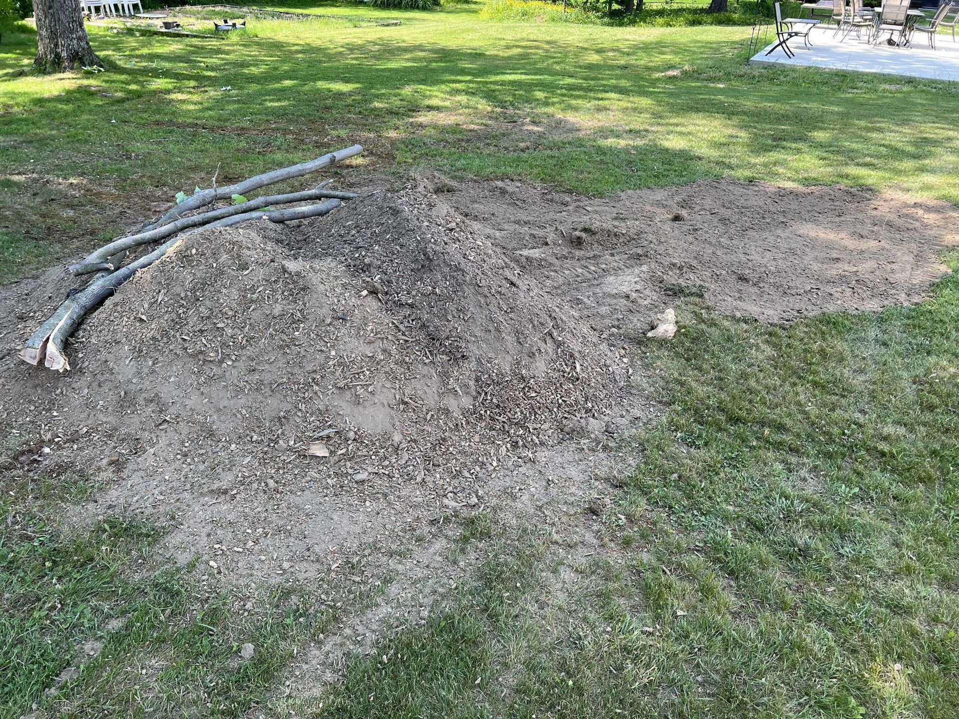 A pile of dirt is sitting in the middle of a lush green field.