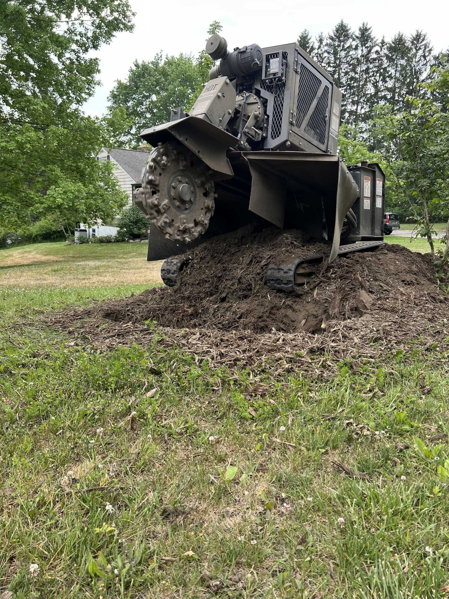 A large machine is sitting on top of a pile of dirt in a grassy field.