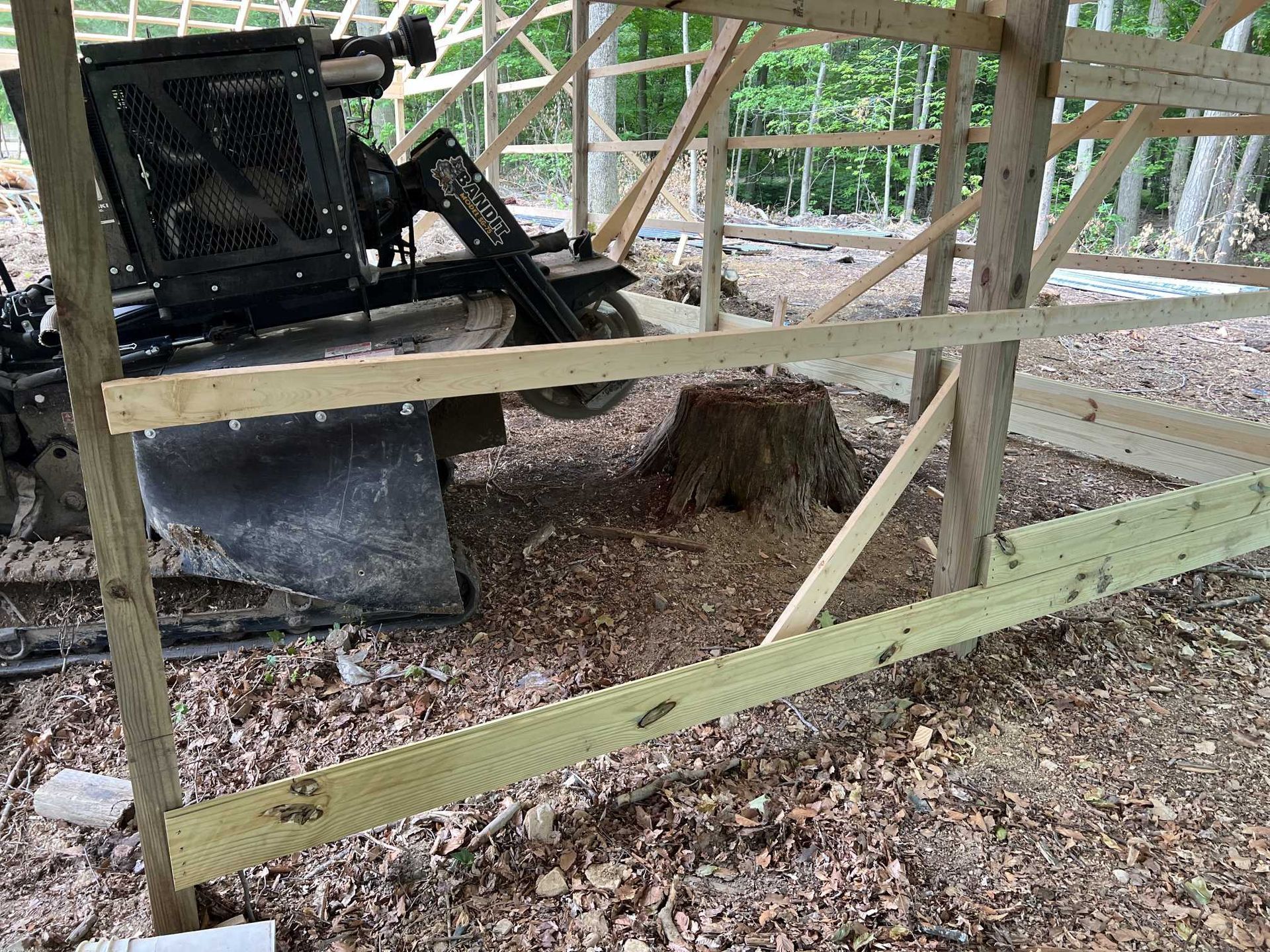 A bulldozer is parked in front of a wooden structure.