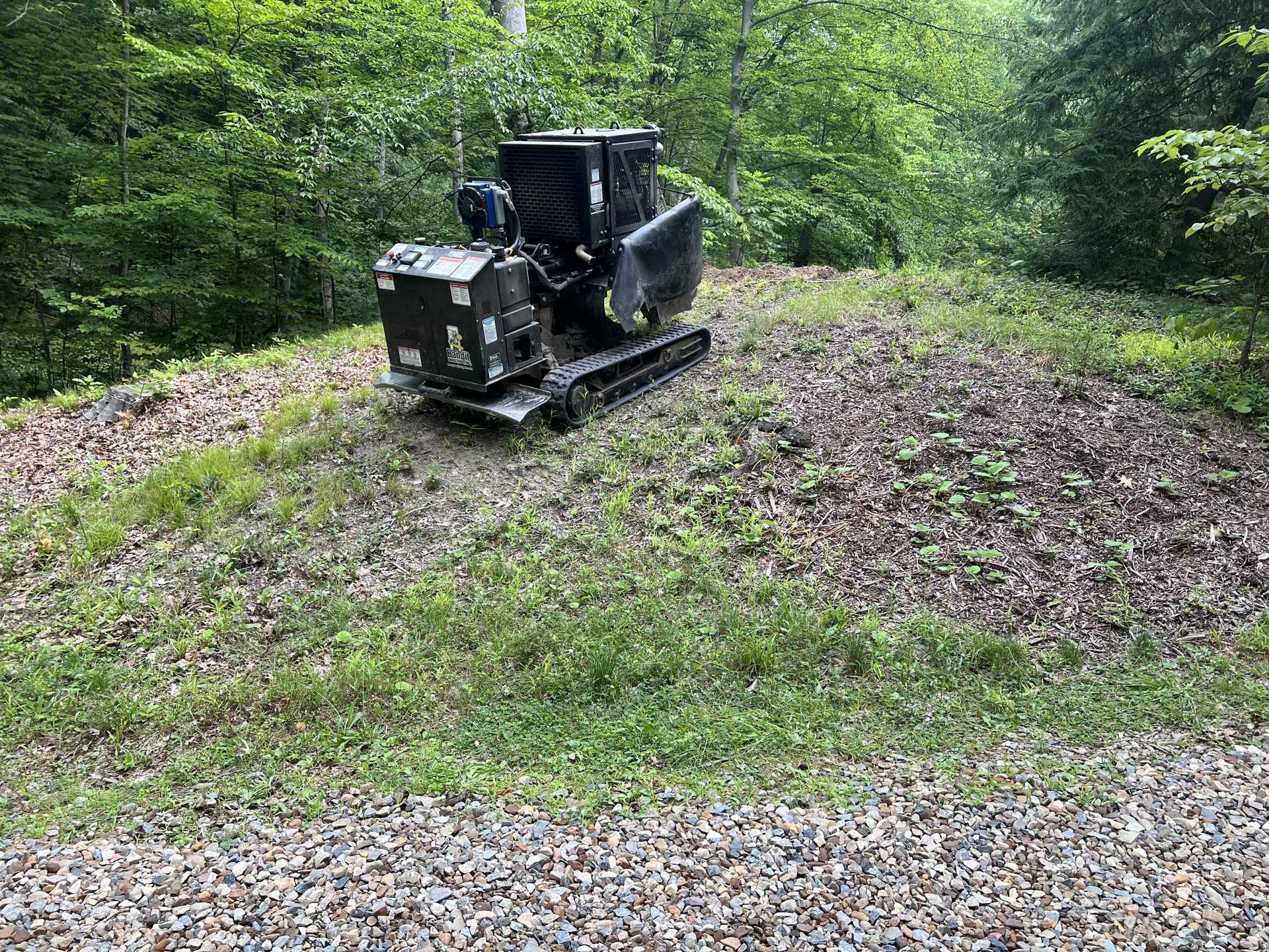 A small tractor is sitting on top of a gravel road.