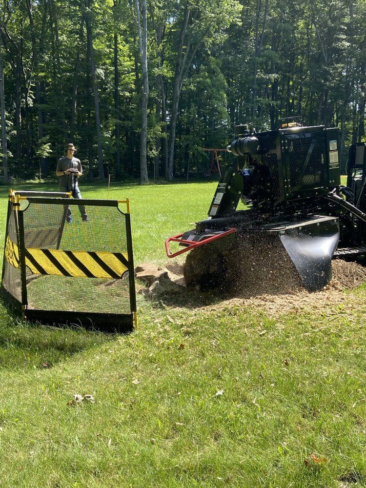 A tractor is stump grinding a tree in a park.