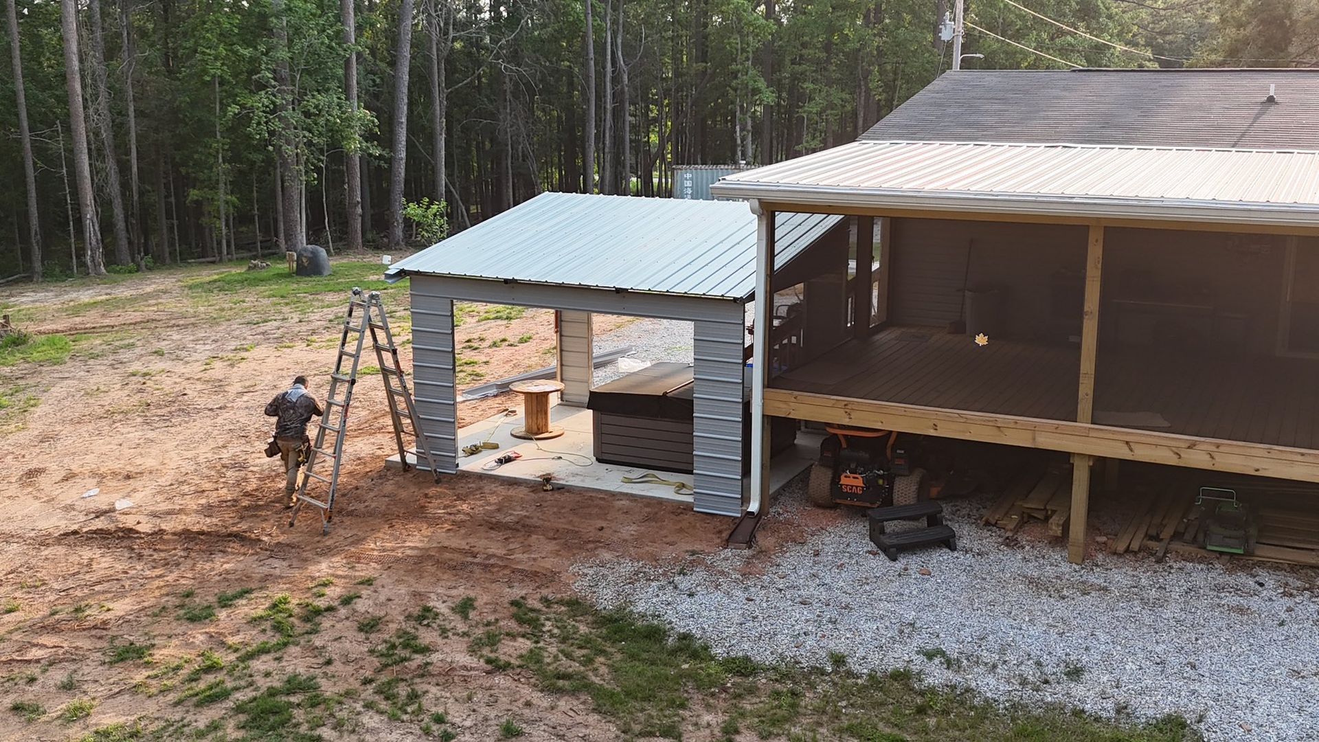 A man constructing a gray shed next to a house with a screened porch, outdoors.