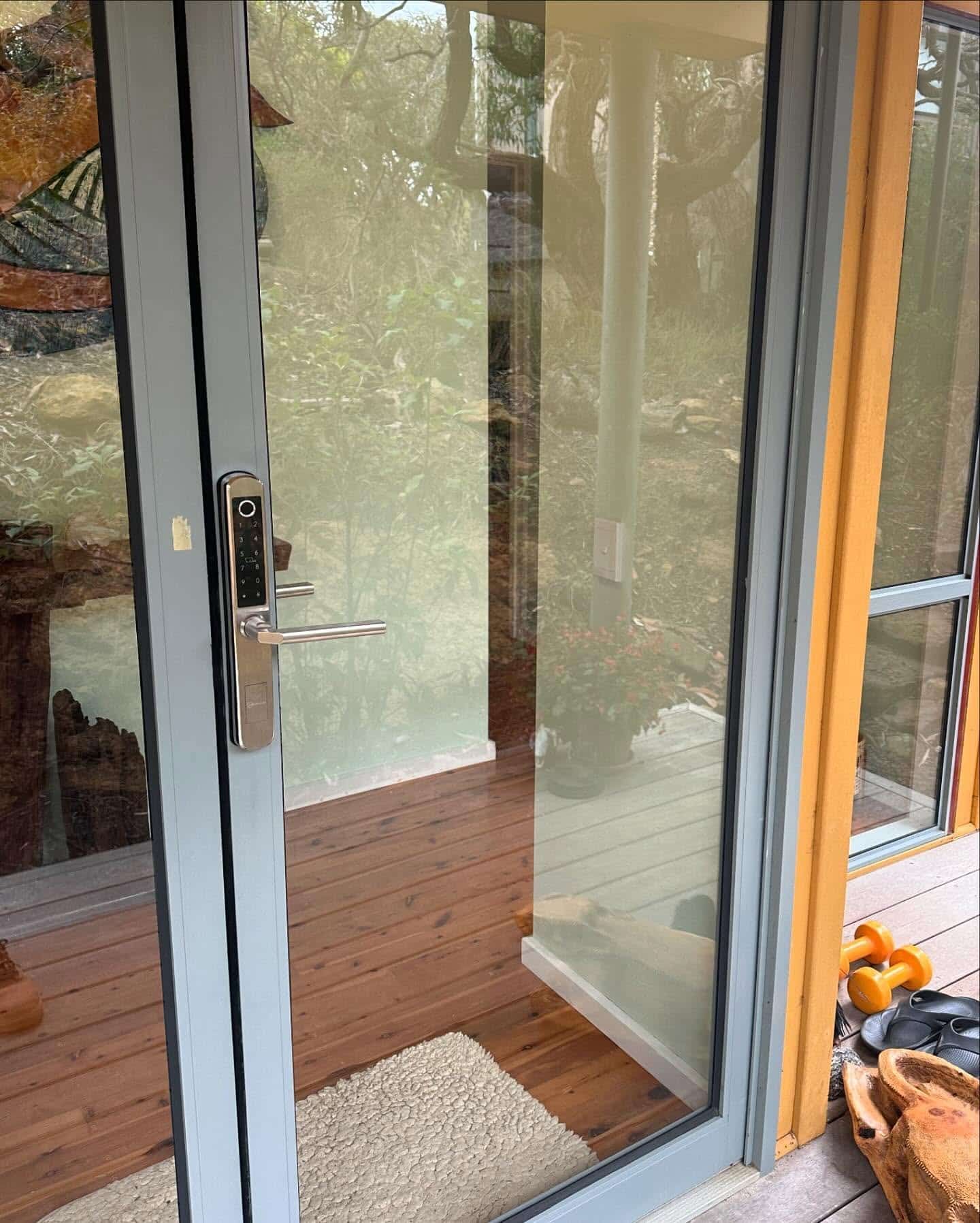 Glass Door With Smart Lock, Grey Frame, Leading to Wooden Deck — Great Ocean Locksmiths in Belmont, VIC