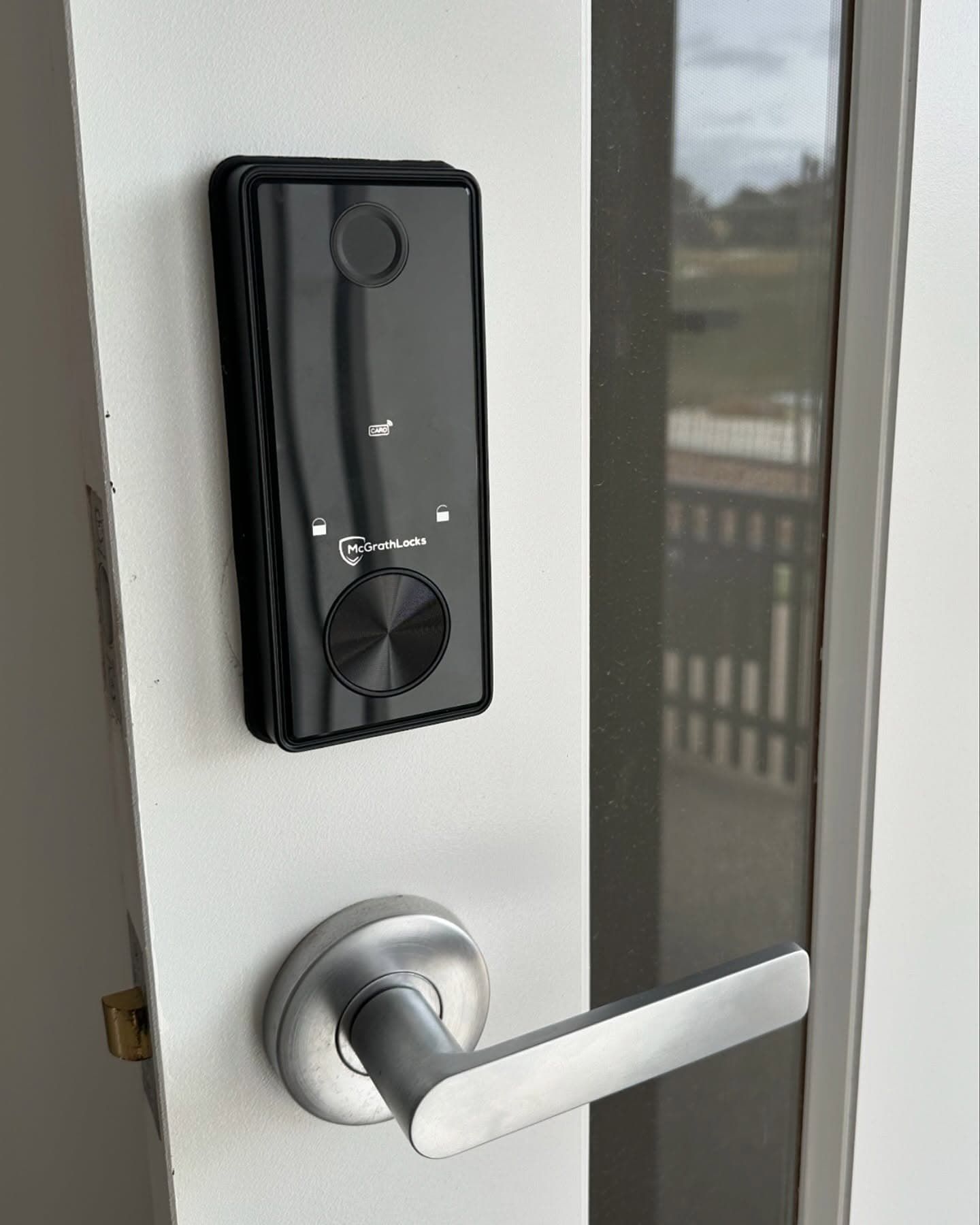 Black smart lock with silver door handle on a white door — Great Ocean Locksmiths in Belmont, VIC