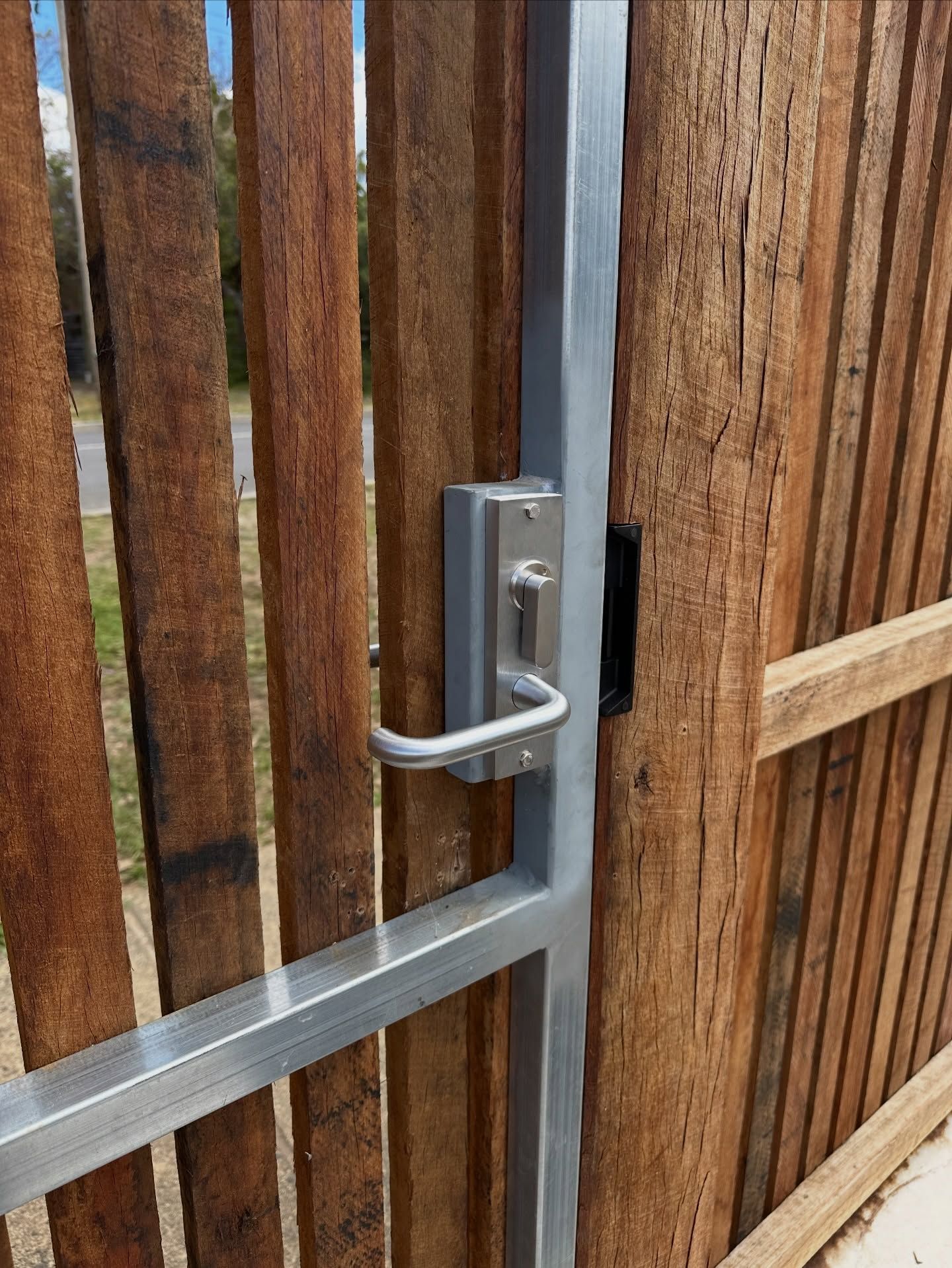 Metal gate with a handle, attached to a wooden fence — Great Ocean Locksmiths in Belmont, VIC