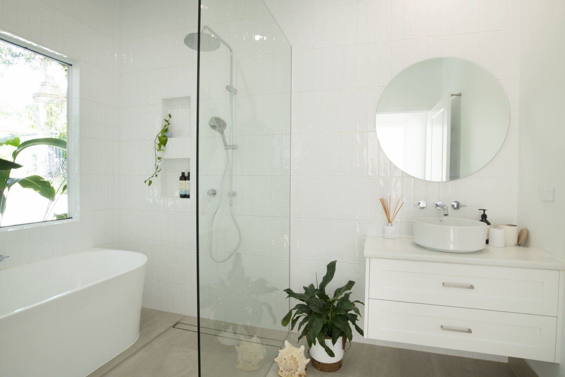 A bathroom with a walk in shower , sink , tub and mirror.