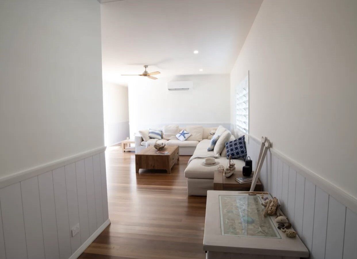 A hallway leading to a living room with a couch and a table