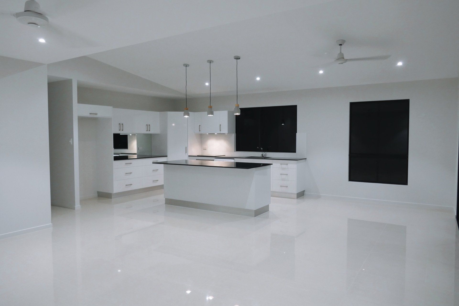An empty kitchen with white cabinets and a large island.