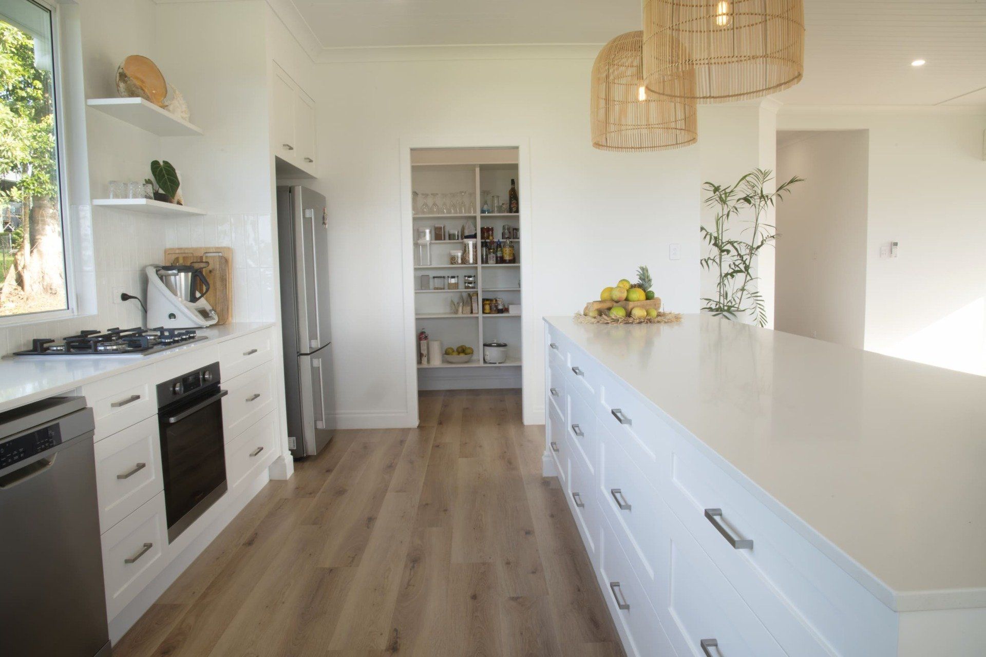 A kitchen with white cabinets , stainless steel appliances , a large island and a pantry.