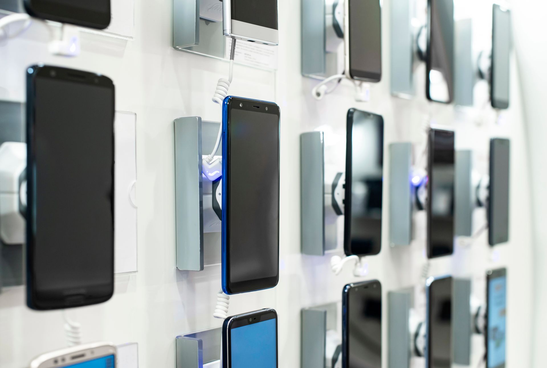 Una fila de teléfonos móviles colgados en la pared de una tienda.