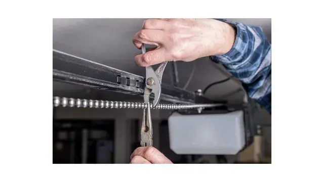 A person is fixing a garage door with a pair of pliers.