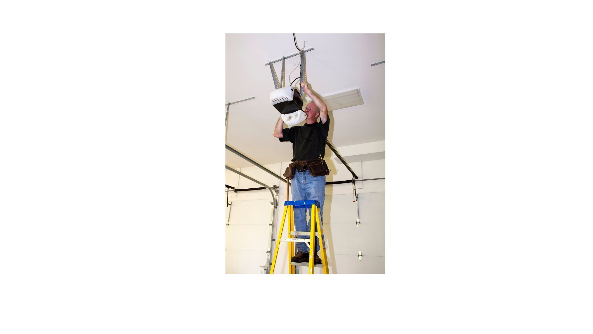 A man is standing on a ladder working on a ceiling fan