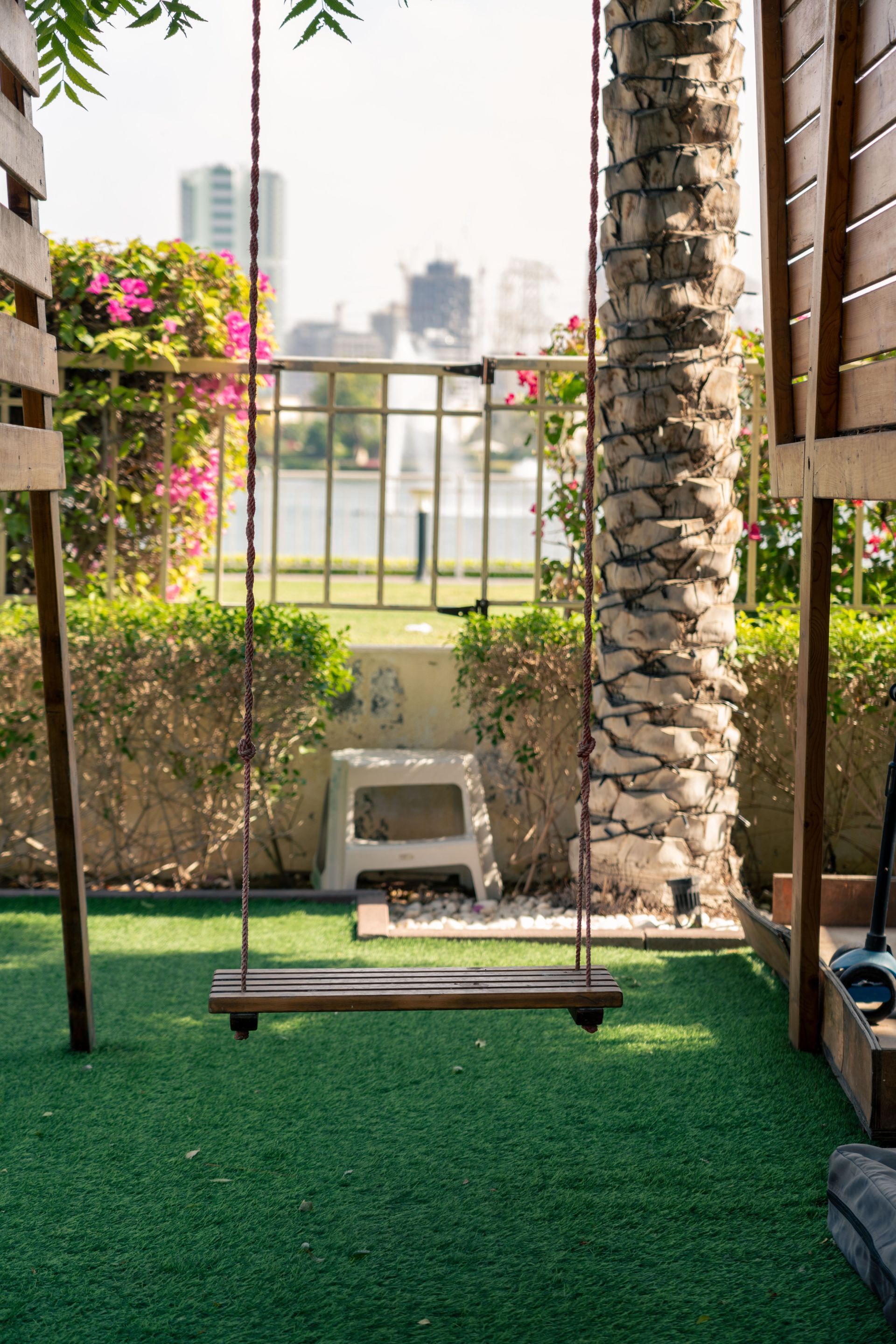 Swing hanging from a tree in an artificial grass lined backyard setting 