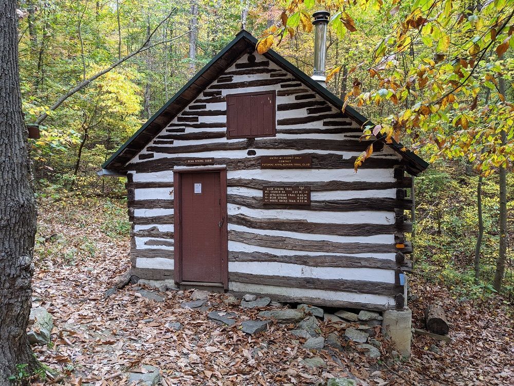 The front view of Bear Spring shelter shows wooden paneling and a wooden door.